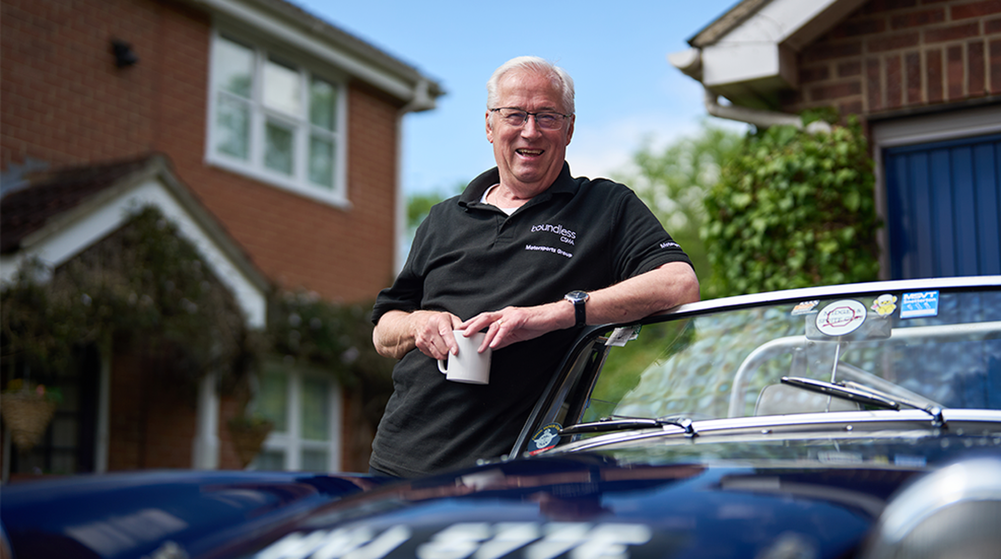 Mike Harrison, chair of the Club Council posing next to classic car