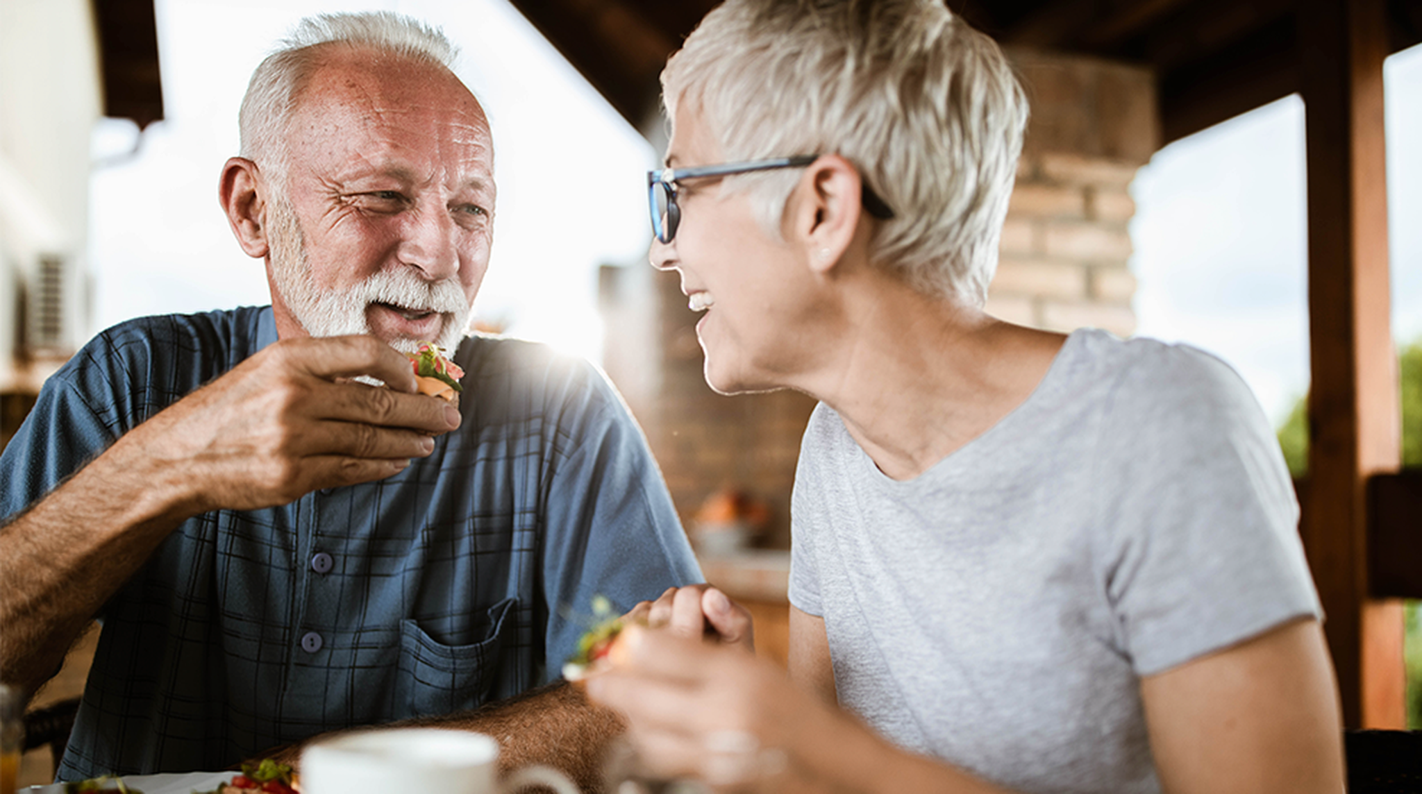 Elderly couple smiling and enjoying a meal together
