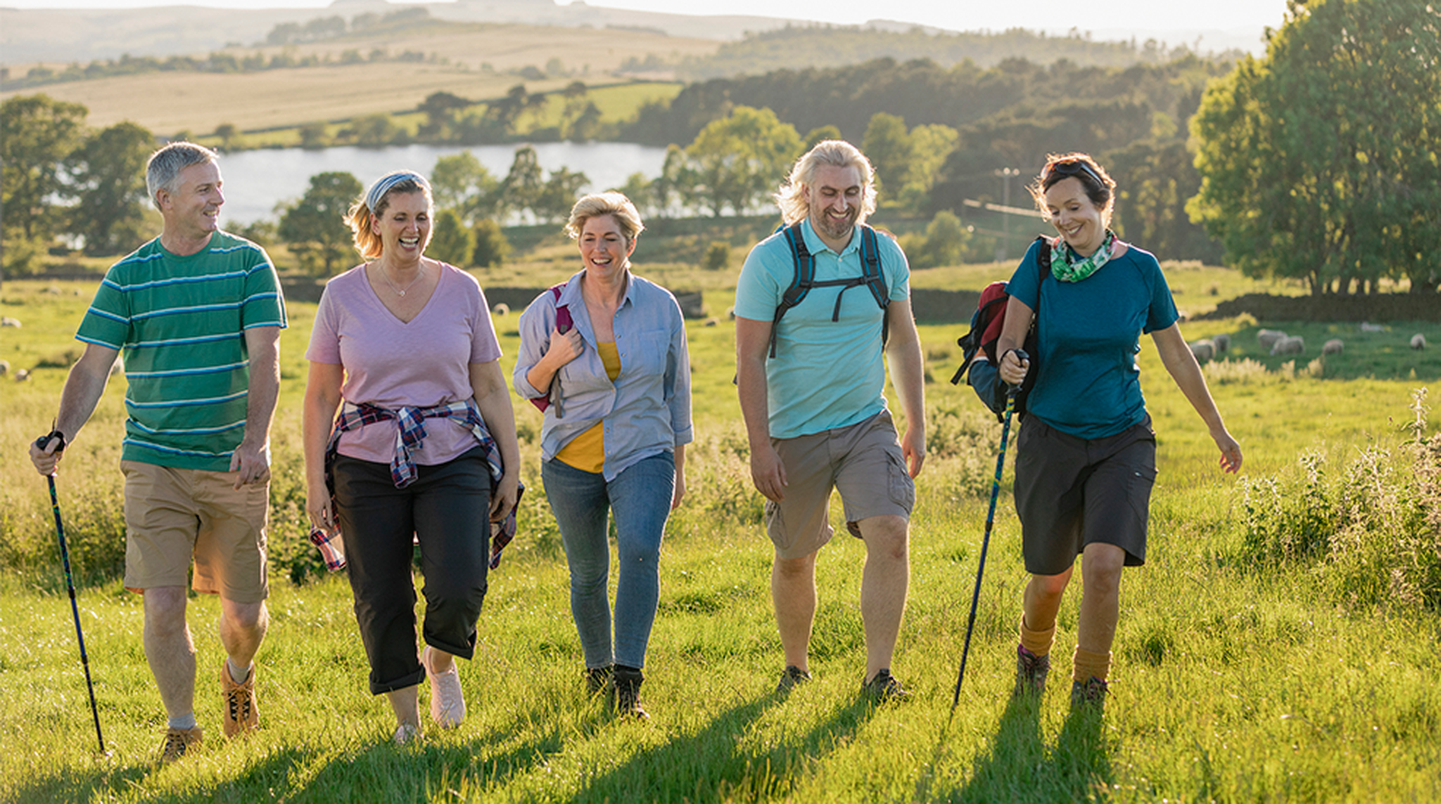 Mature Caucasian group of friends out walking in the countryside with a stunning view behind them.