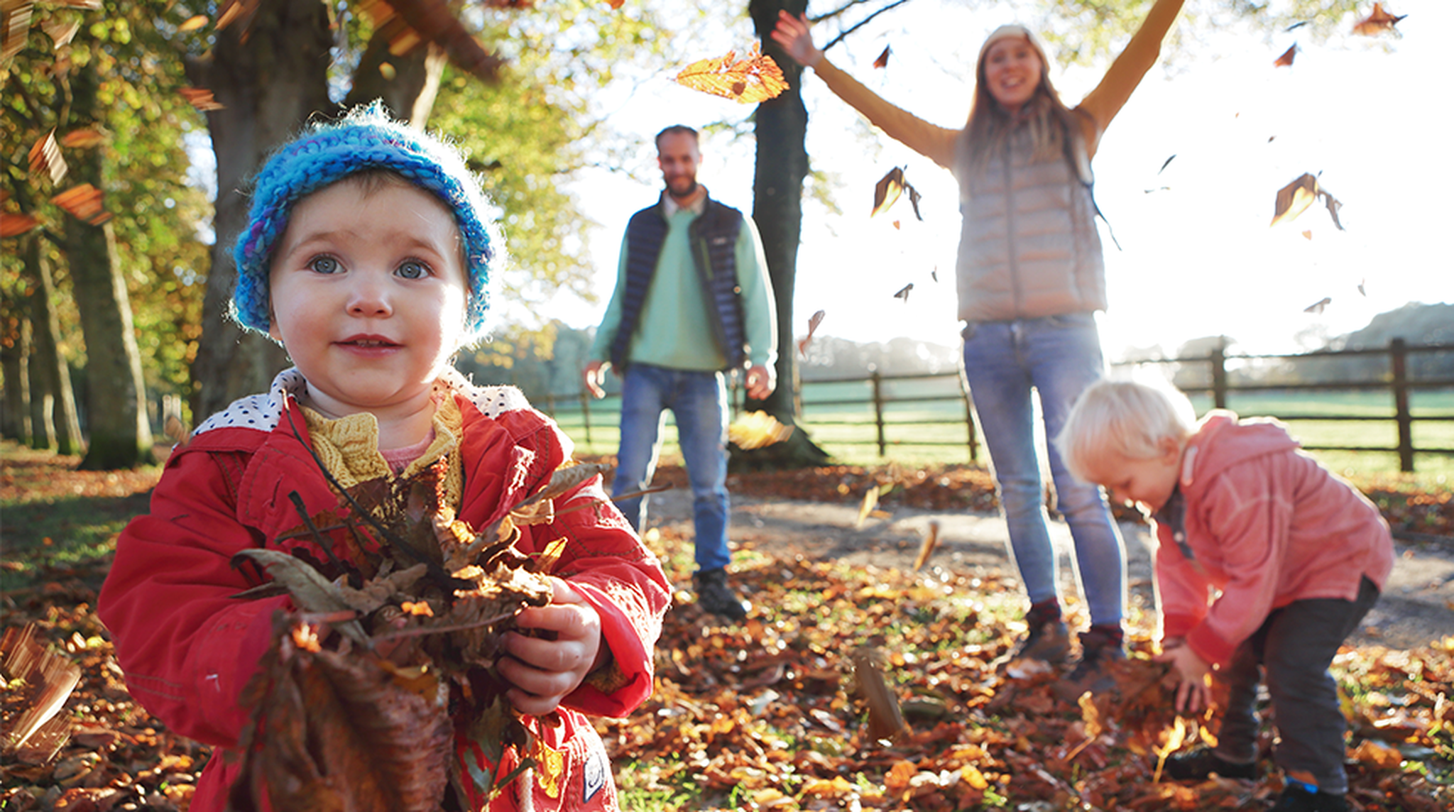 Family playing with fallen leaves in park