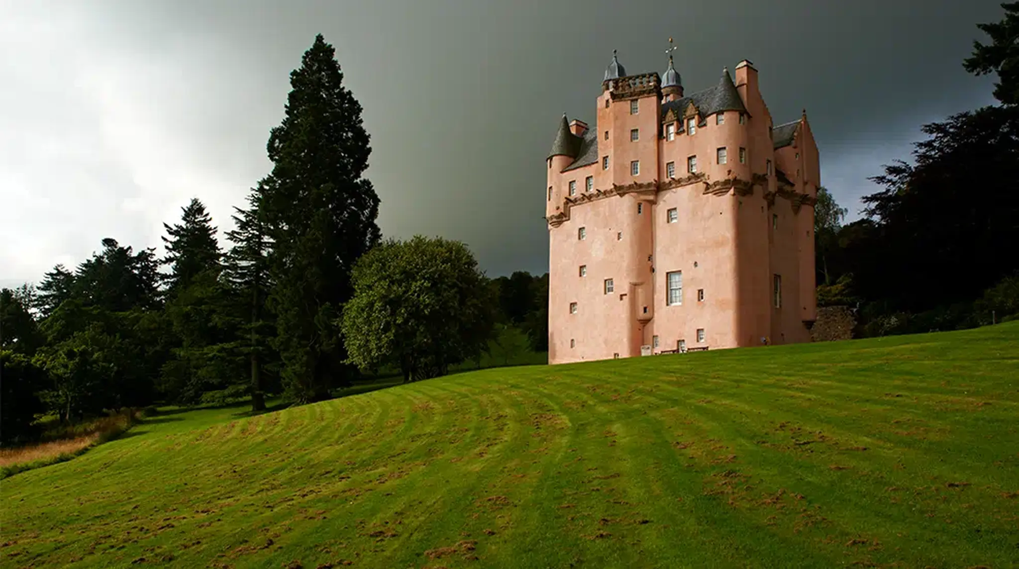 A pink castle stands on a green hill