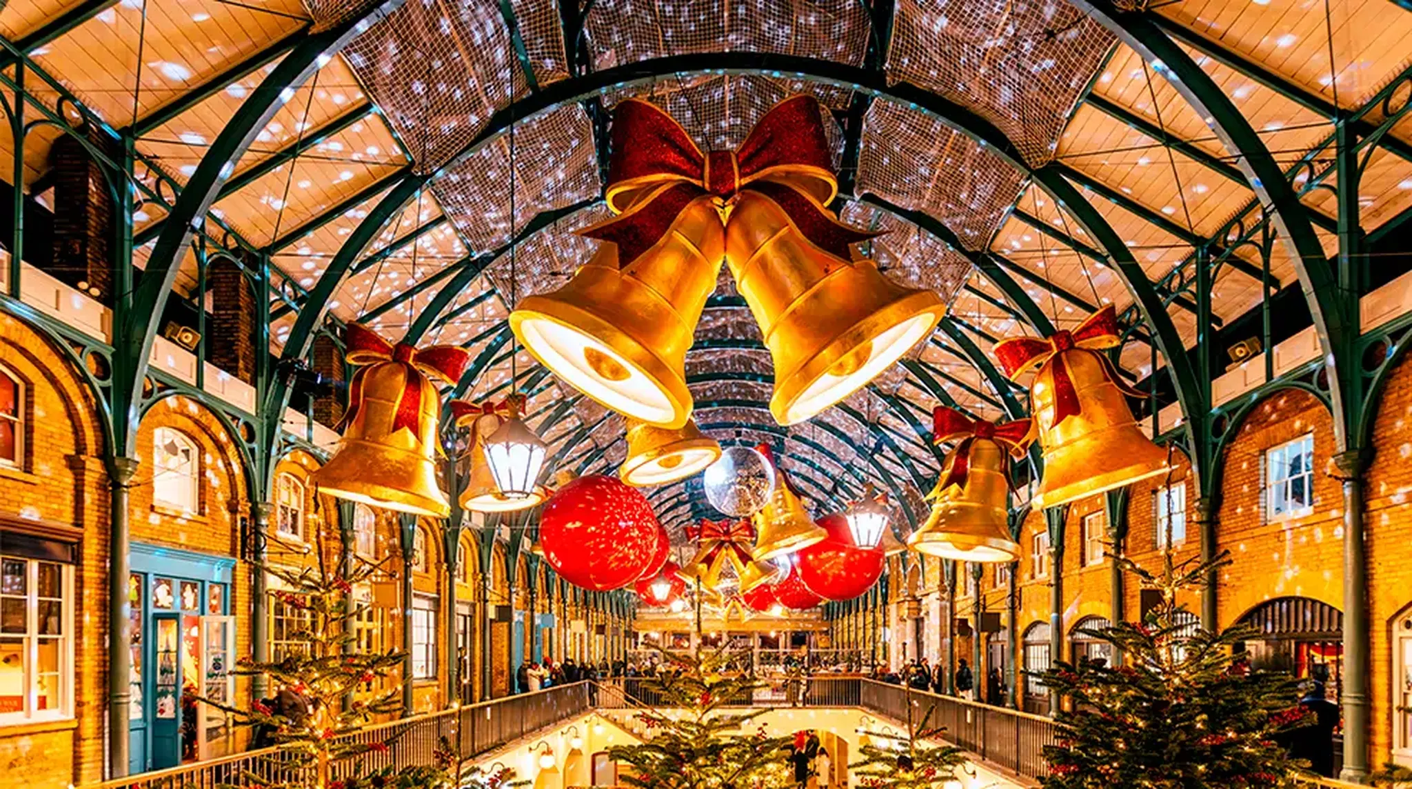 Decorative bells, red ornaments, and lights adorn a festive indoor market