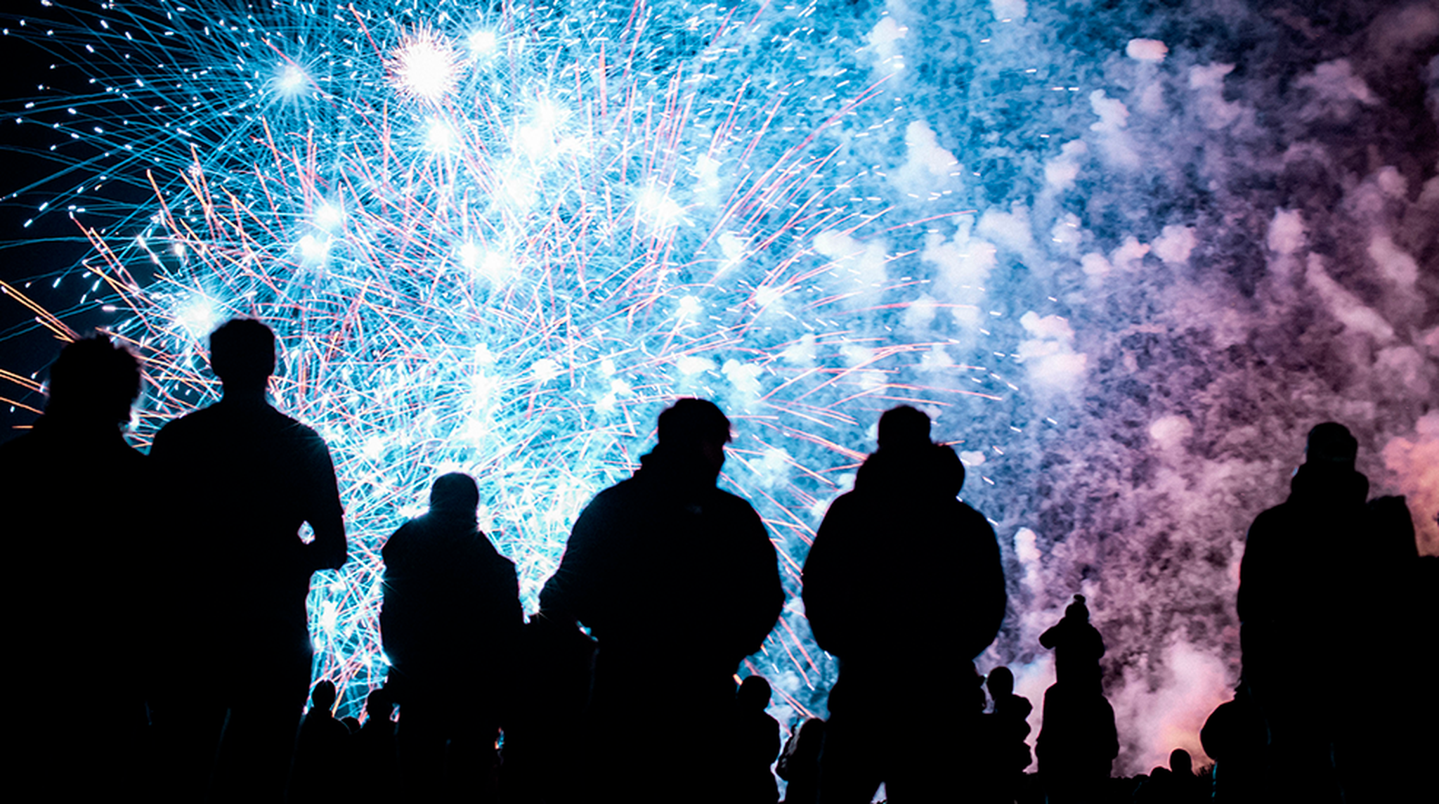 Crowd in silhouette watching firework display