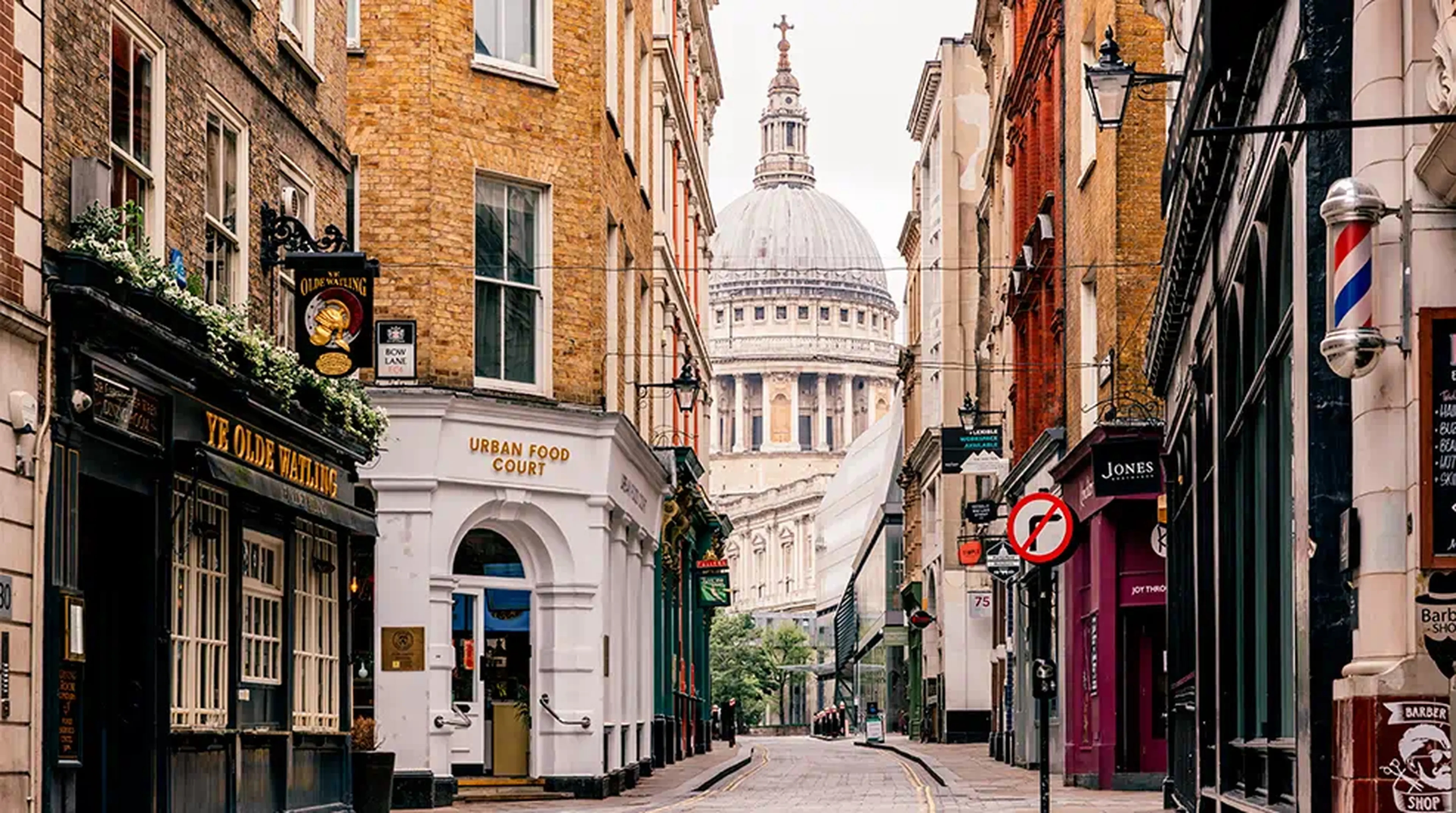 Narrow London street with shops and pubs, leading to St. Paul's Cathedral