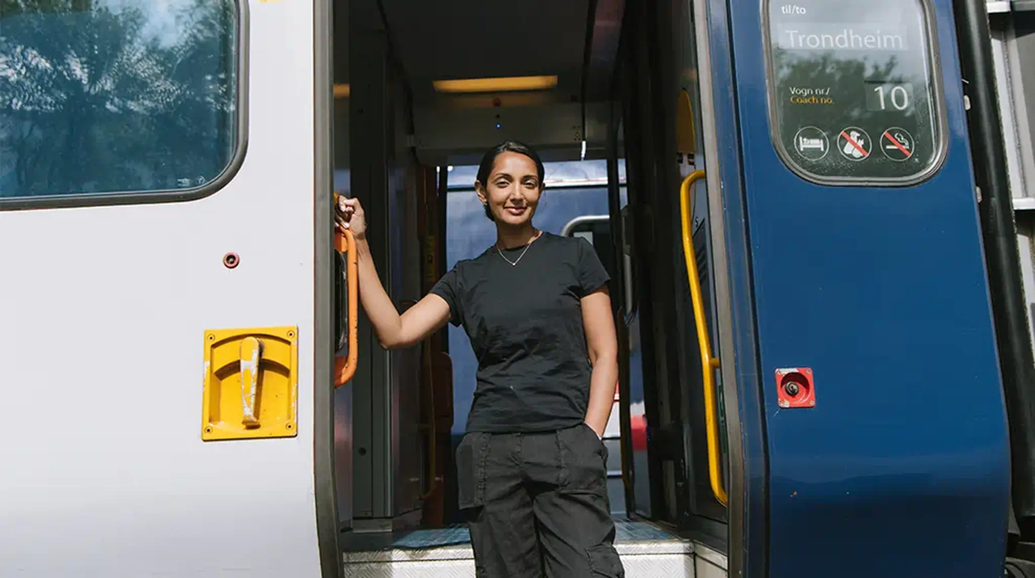 Person standing confidently in the doorway of a train with a sign indicating the destination as Trondheim