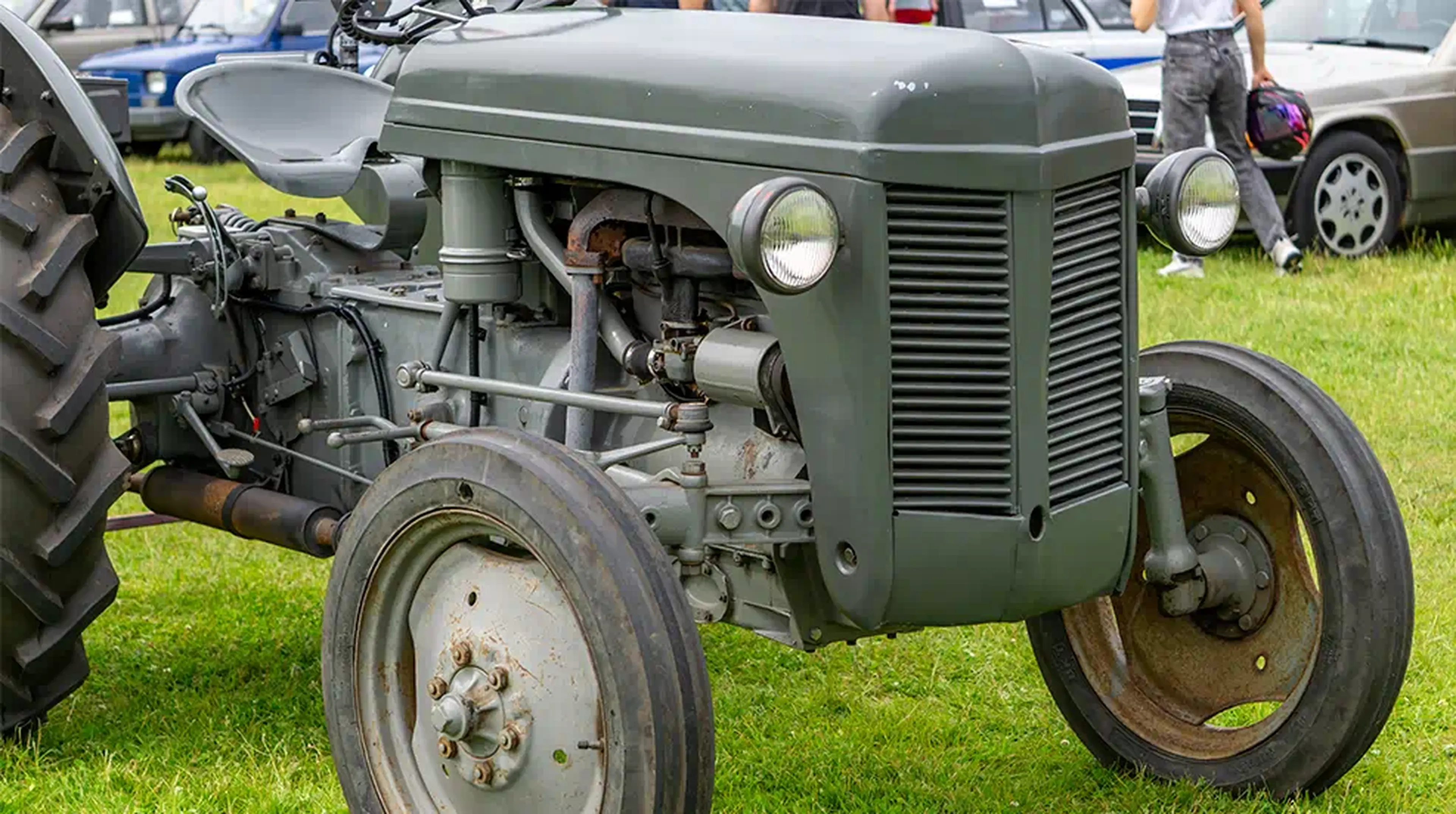 A vintage gray tractor with large rear tires and smaller front tires parked on grass
