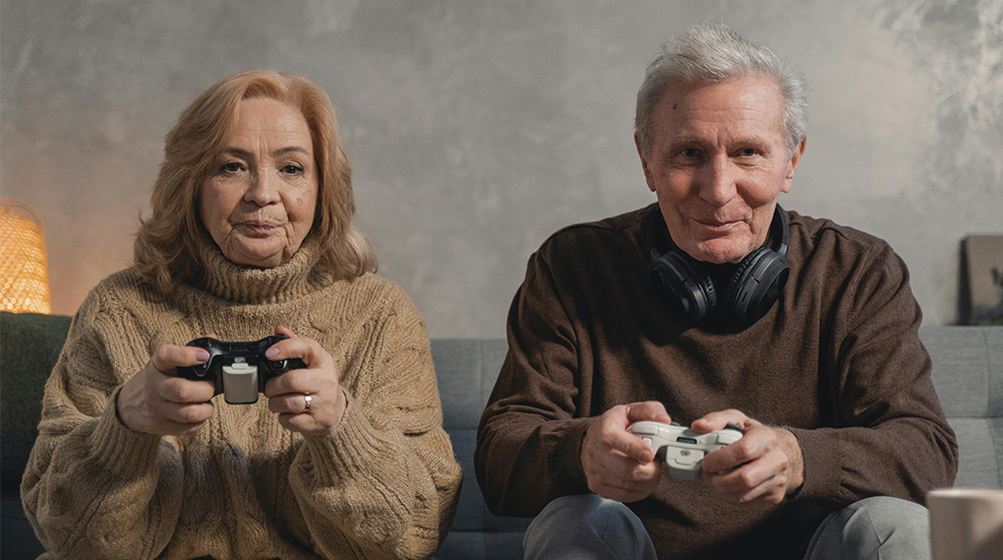 Senior couple playing video games together with pizza on the table, enjoying leisure time at home