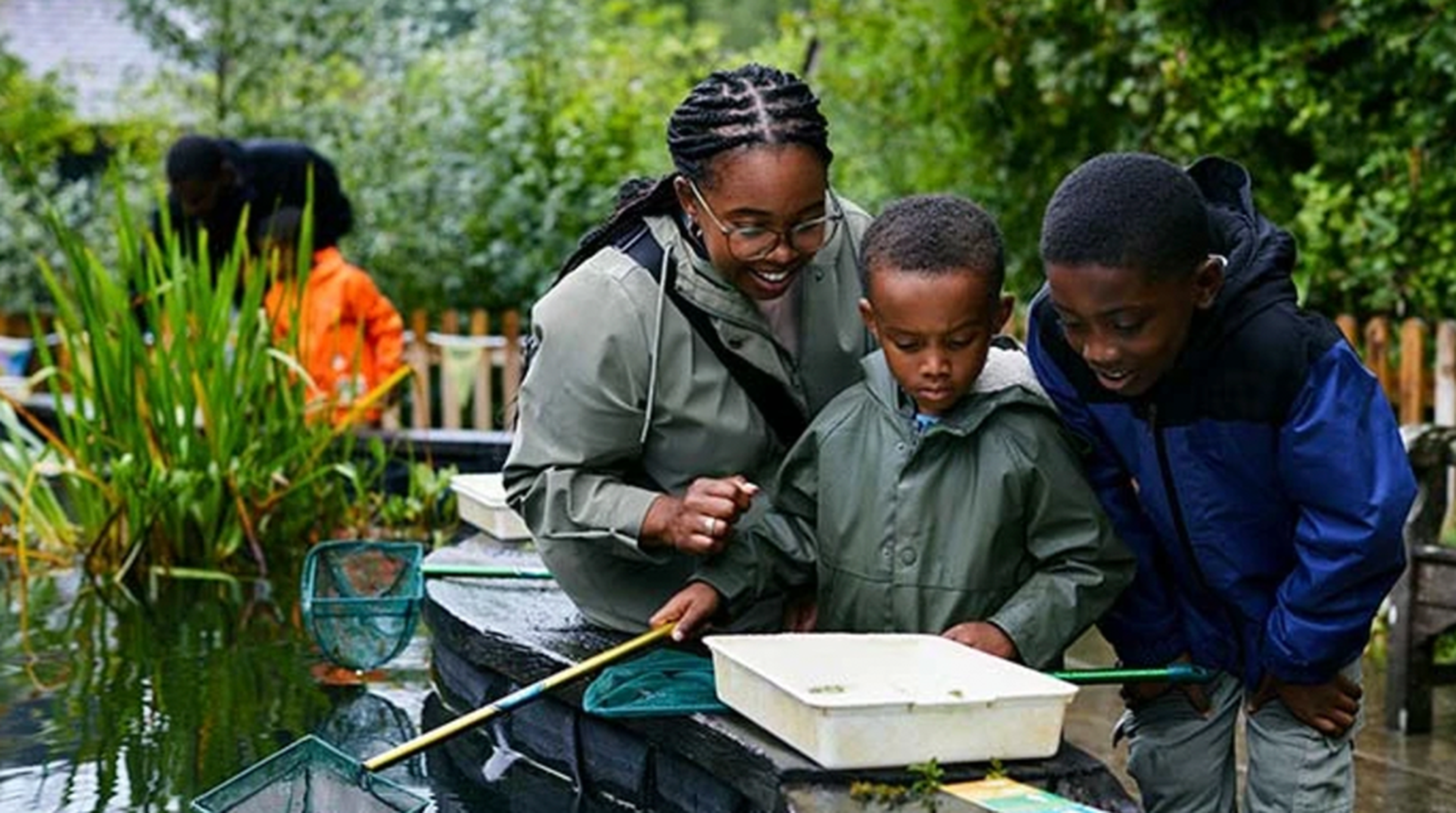 Parents and their child taking part in WWT pond dipping activity