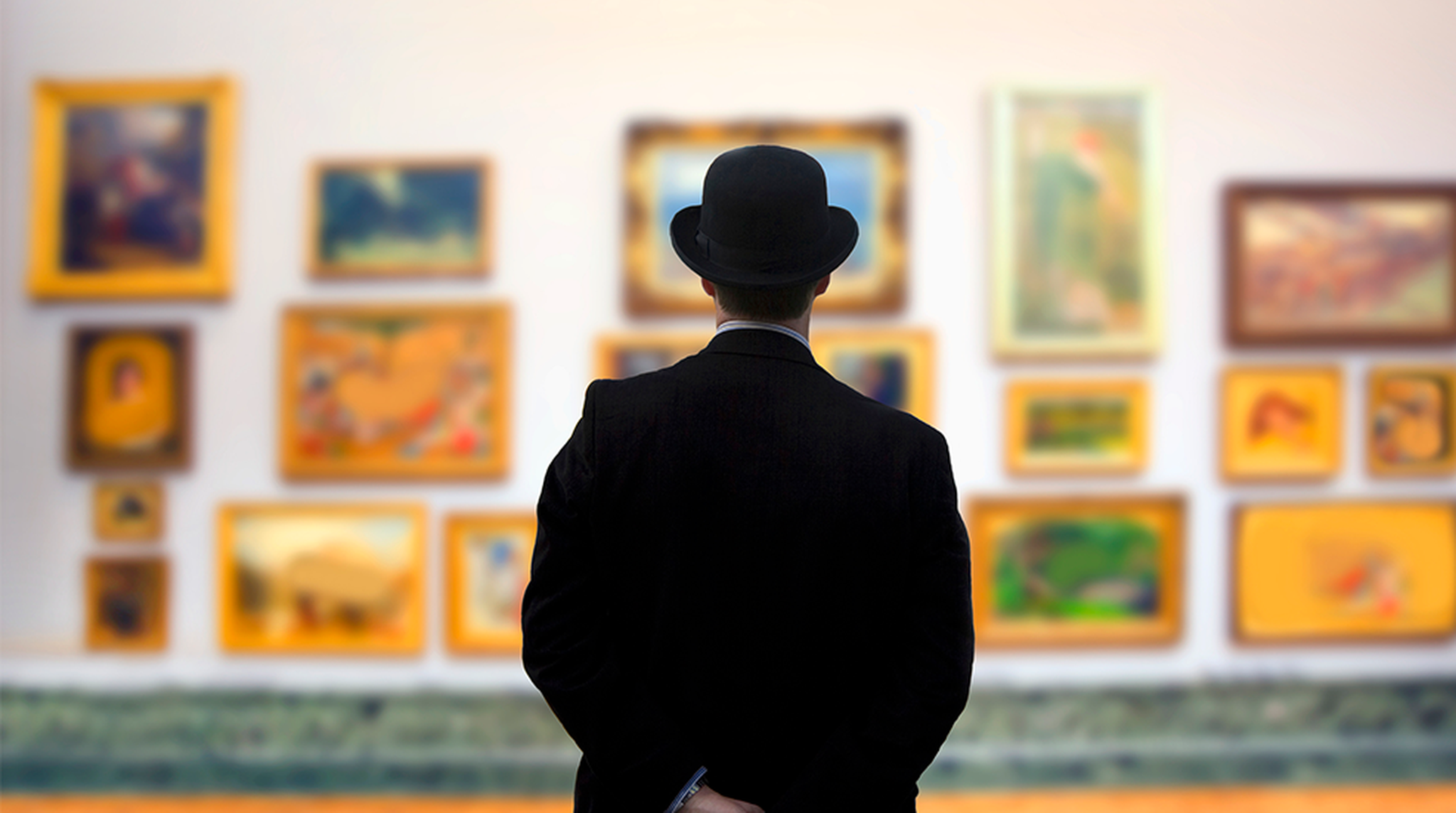 A man in suit wearing bowler hat standing in art gallery that is out of focus