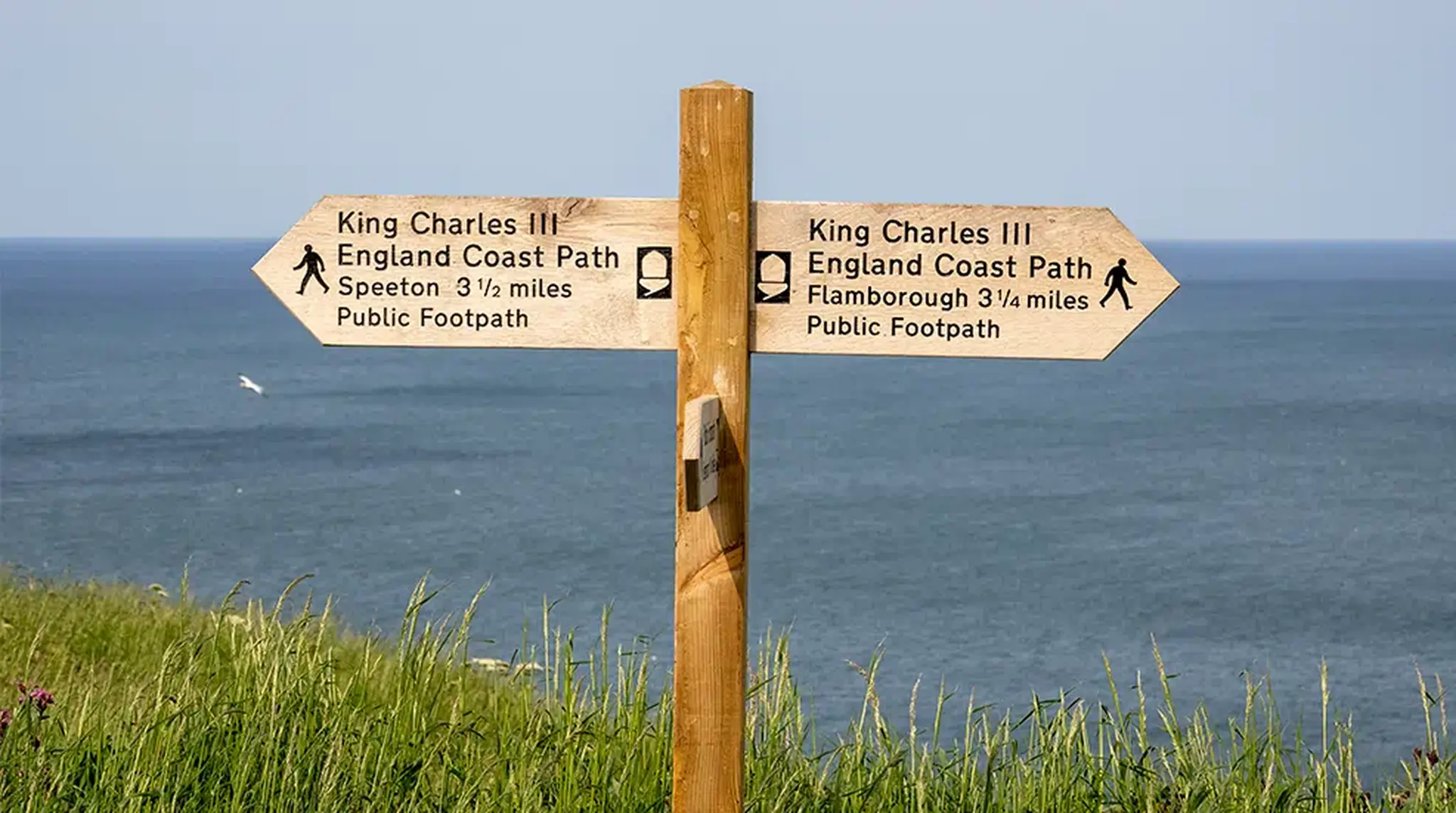 Wooden signpost with arrows pointing to Speeton and Flamborough along King Charles III England Coast Path