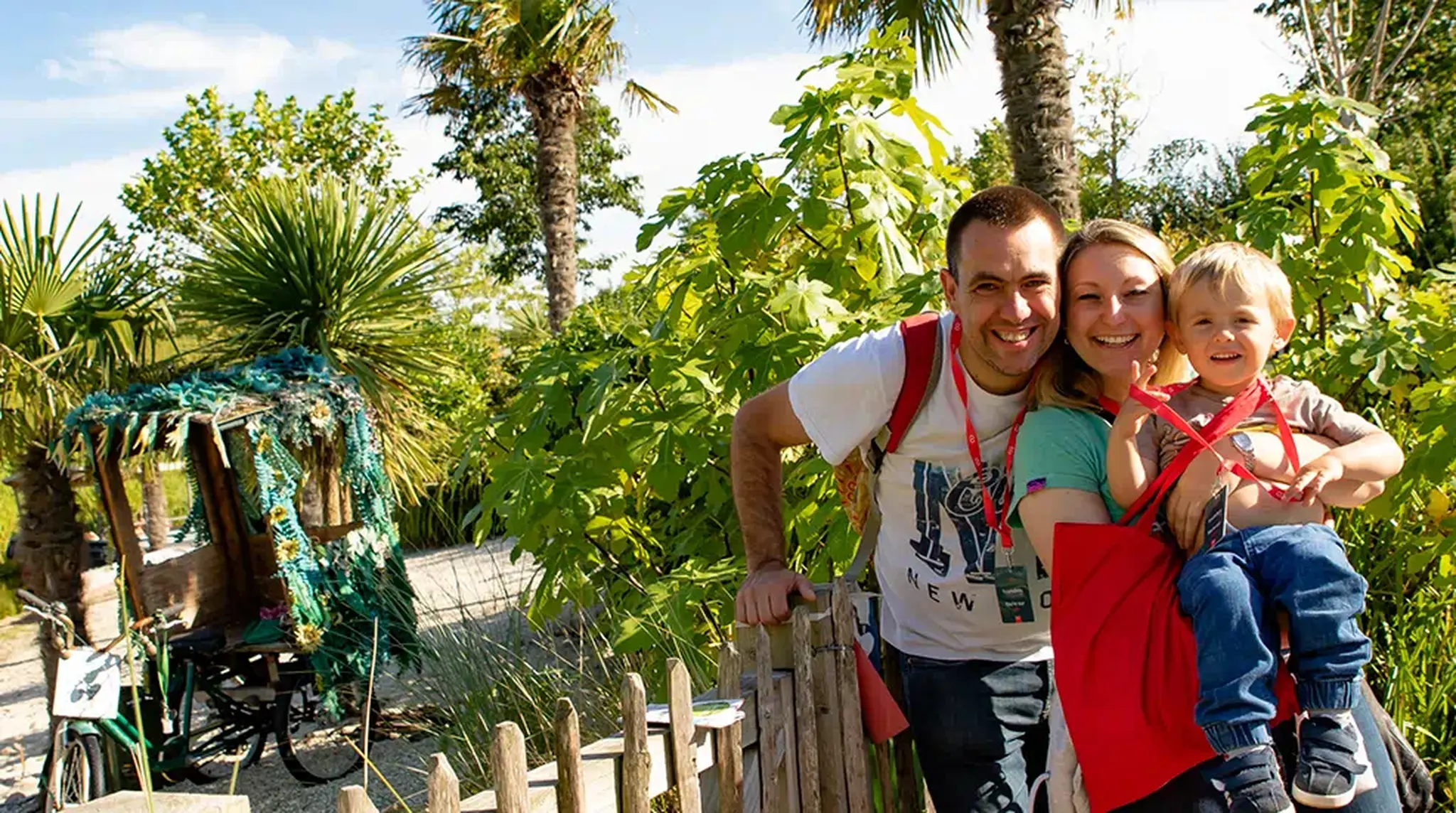 A smiling family of three poses in a garden at Chester Zoo