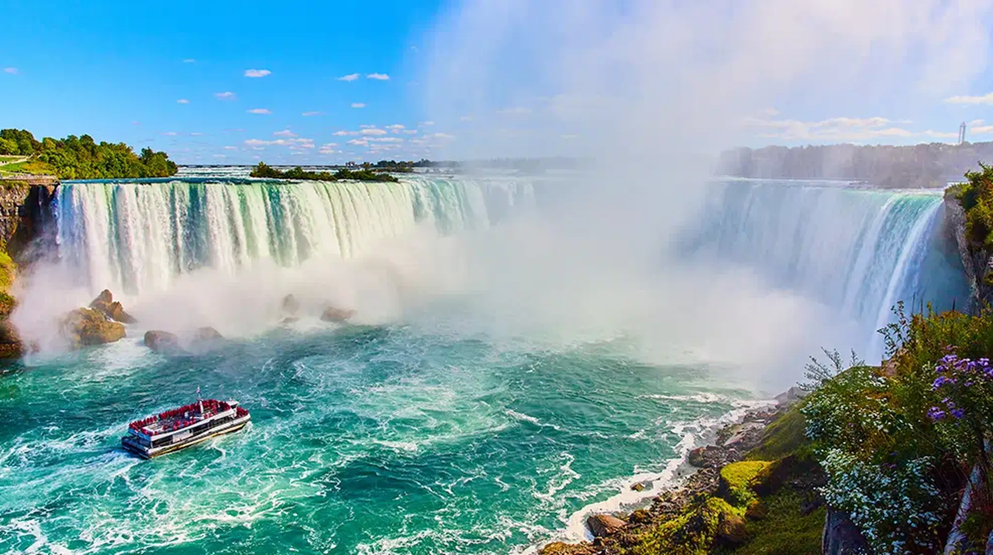 A boat sails near the misty base of the Niagara Falls