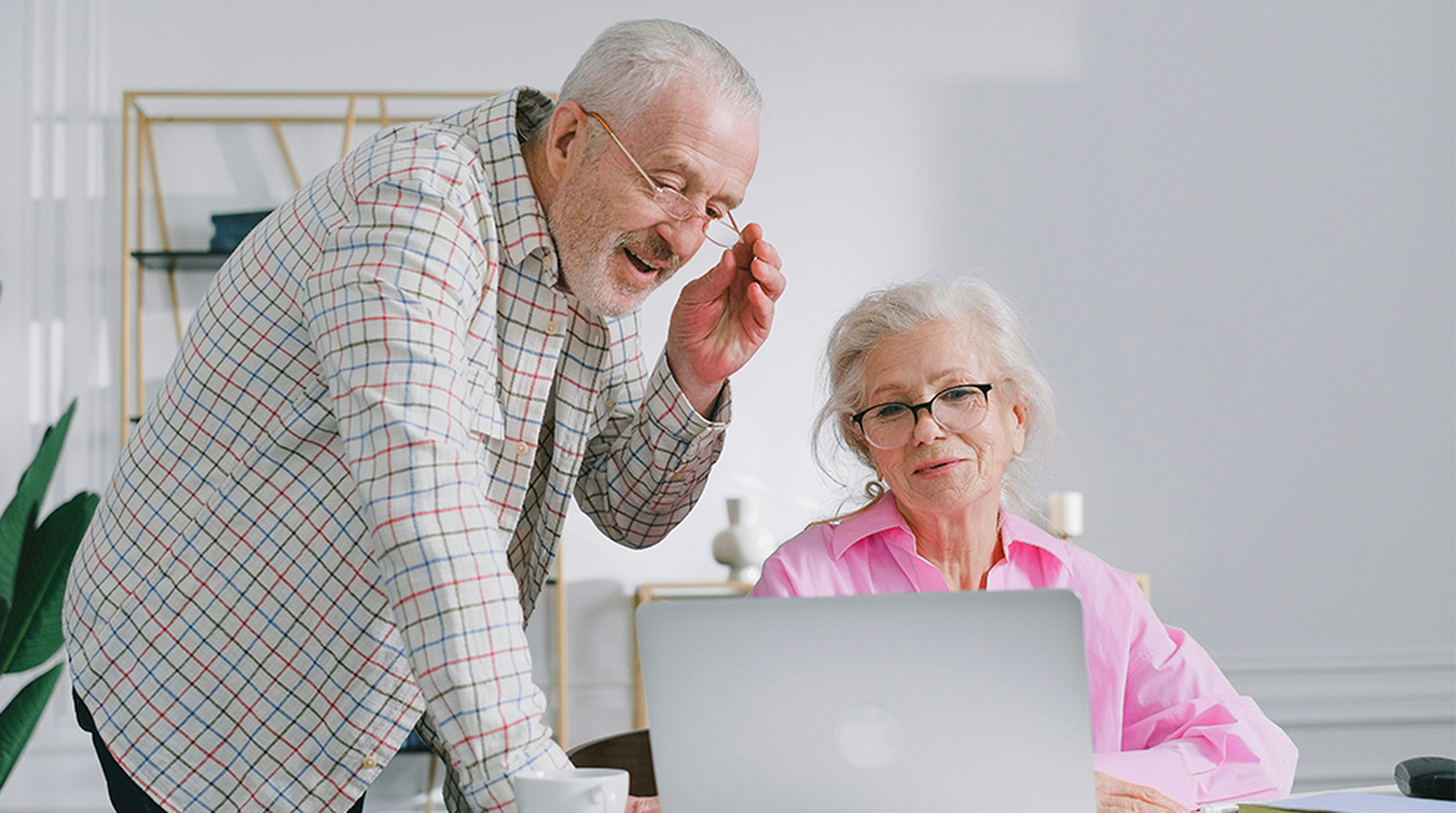 Senior couple enjoying a conversation while using a laptop indoors, showcasing active lifestyle.
