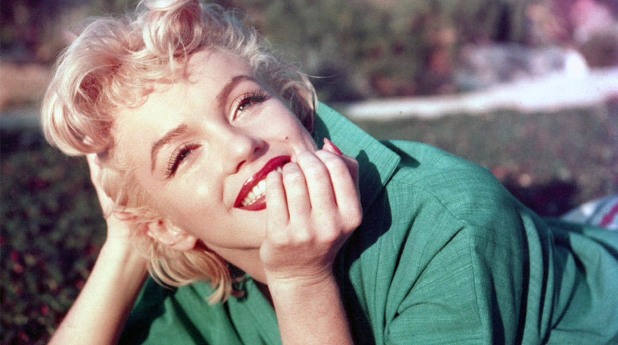 Actress Marilyn Monroe poses for a portrait laying on the grass in 1954 in Palm Springs, California