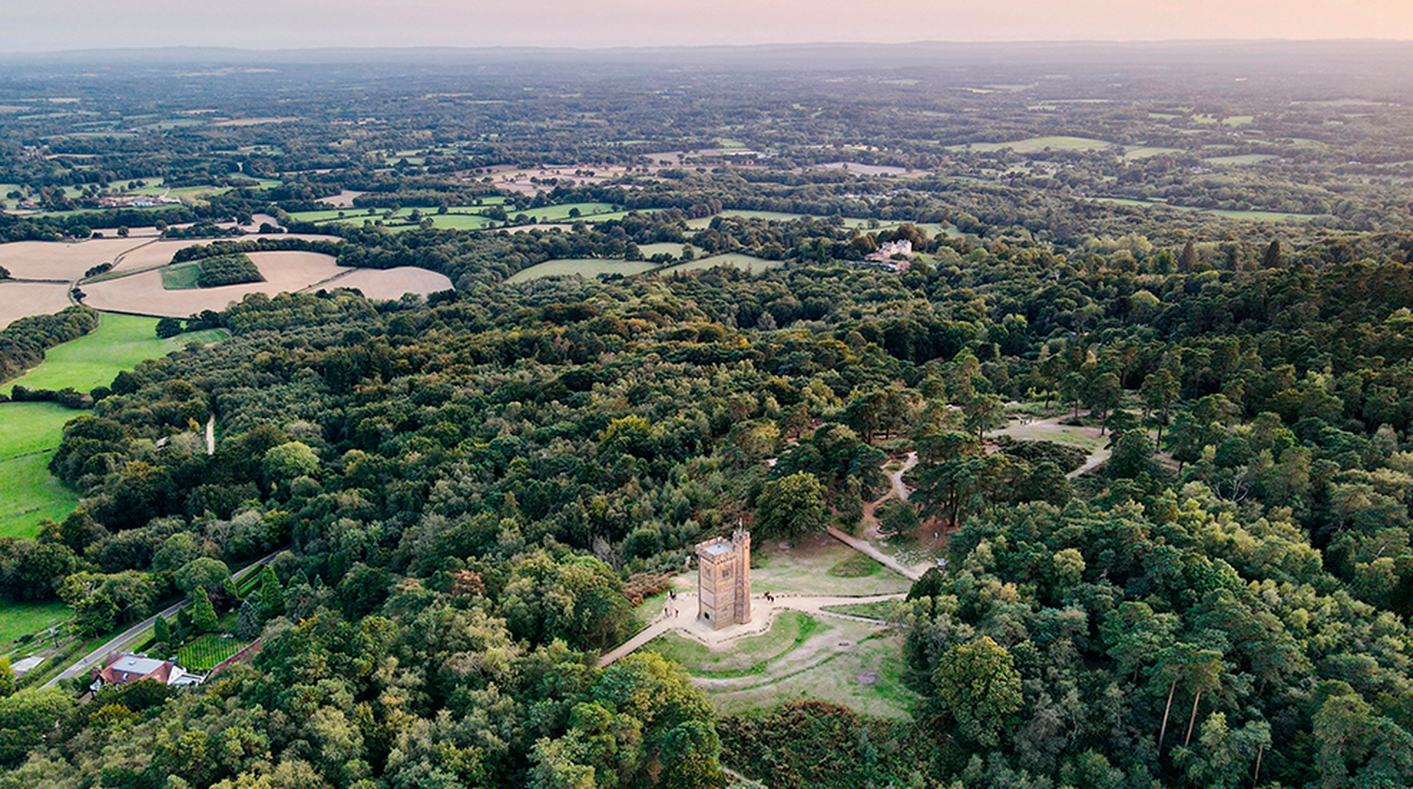 Stunning aerial view of Leith Hill Tower surrounded by lush woodlands in Surrey, England.