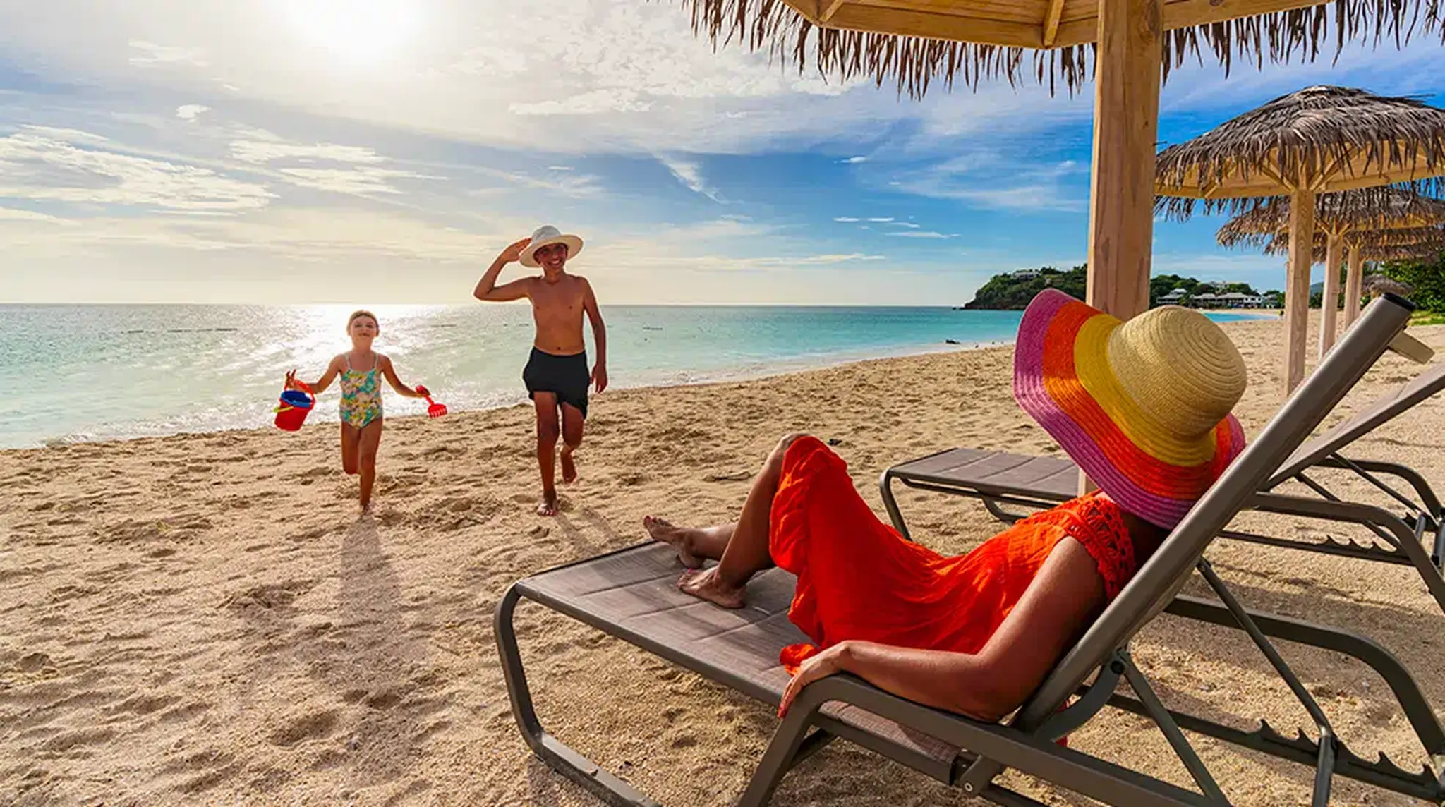 Woman relaxing on a beach chair watching a man and child holding buckets