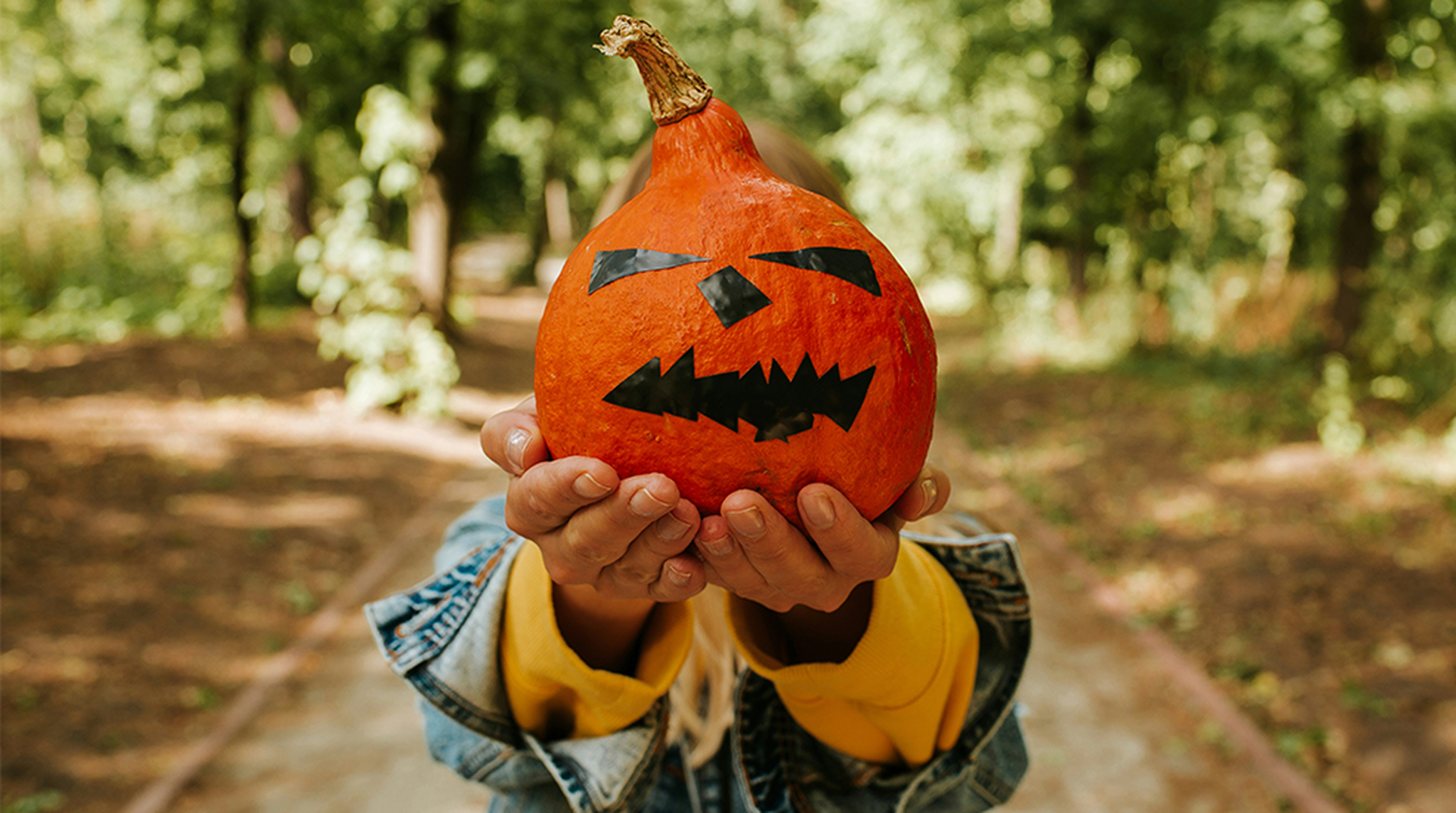 Person holding up a pumpkin to cover their face