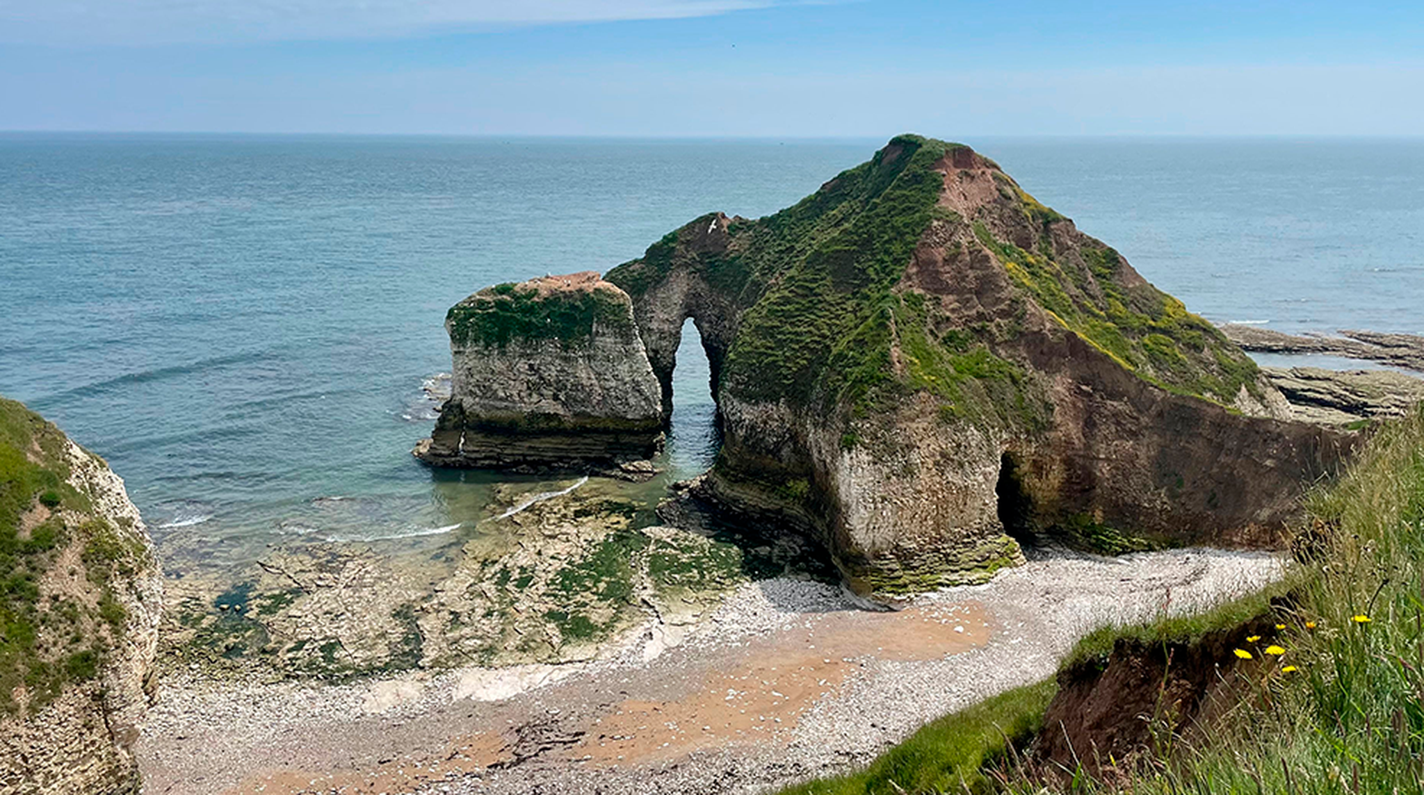 Discover the serene beauty of Flamborough Head's unique coastal rock formation under a bright blue sky.