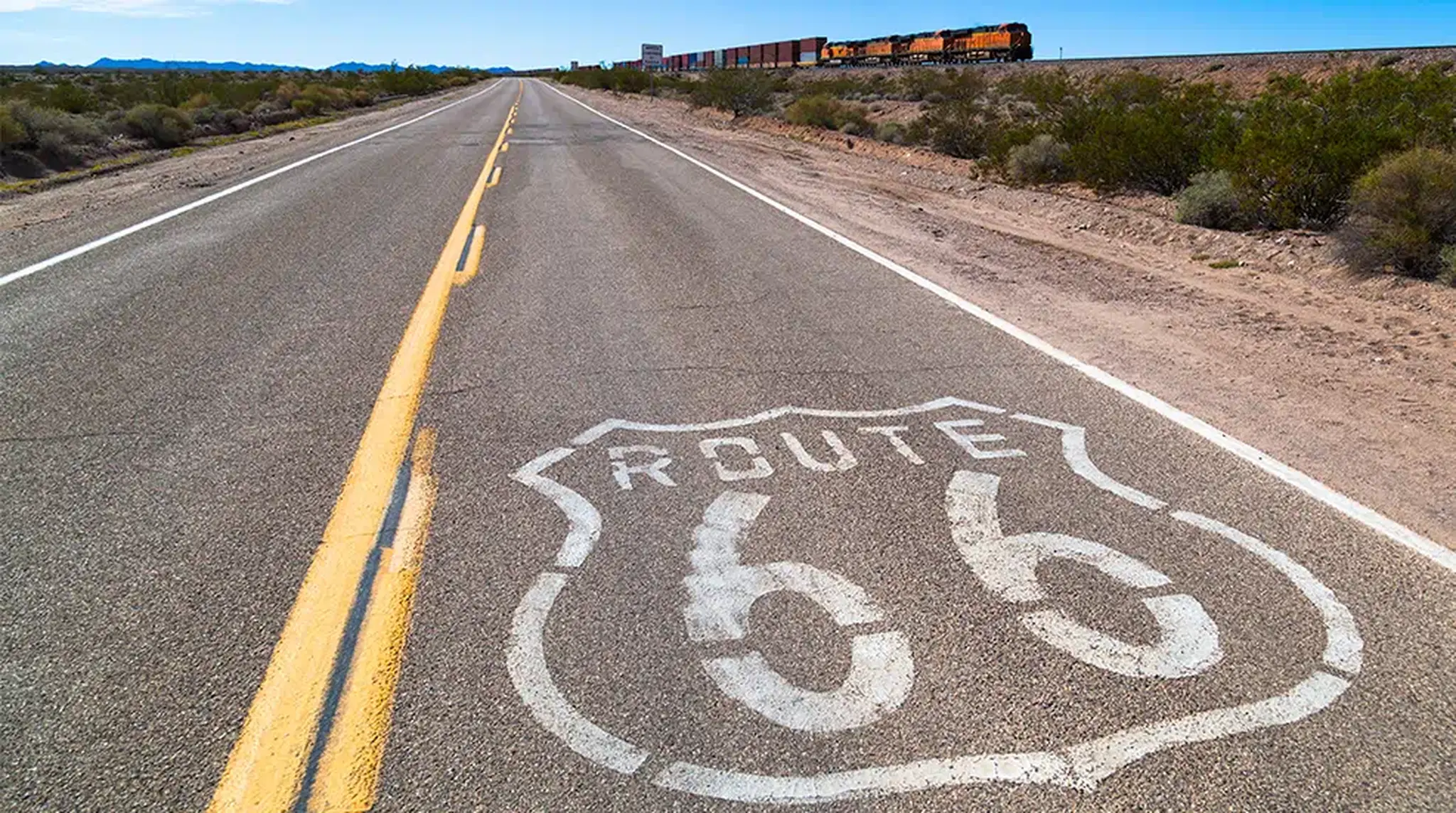 "Route 66 sign on a deserted highway with a distant train