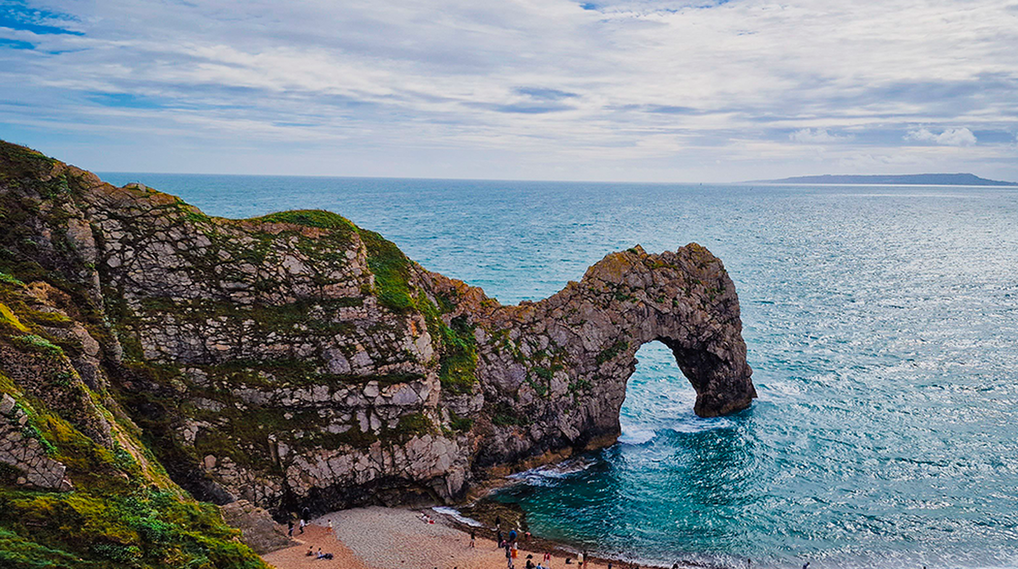 Breathtaking aerial view of Durdle Door along the Jurassic Coast with cloudy skies.