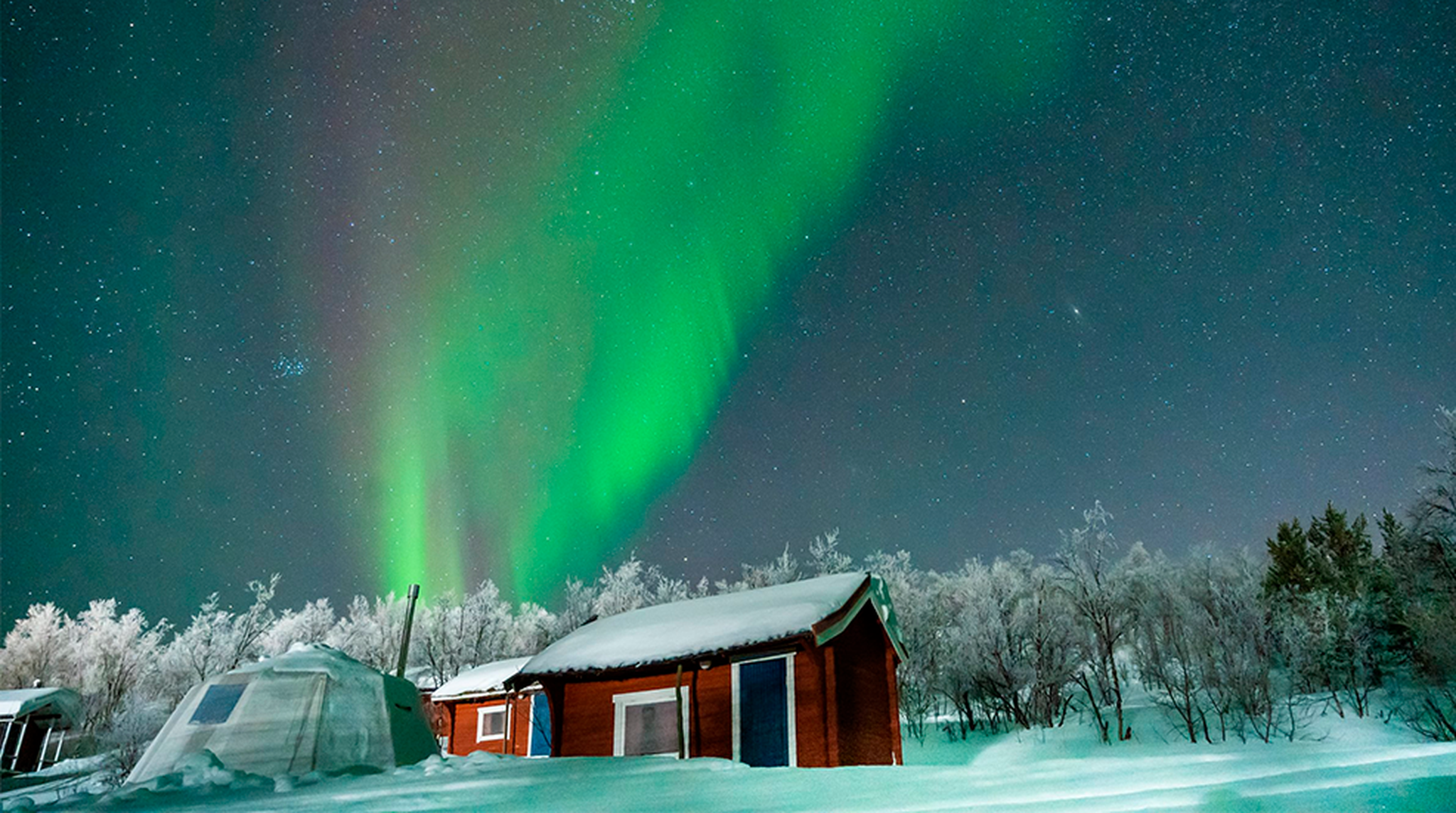 Northern Lights visible above a cabin in Norway