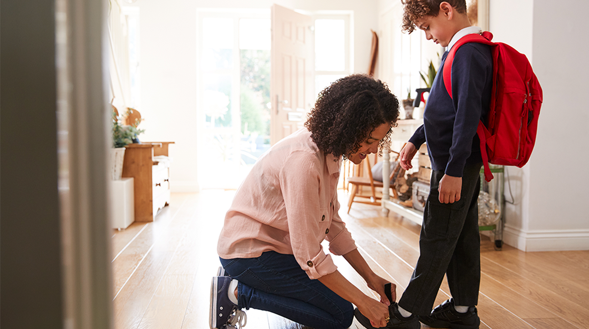 Mother putting on son's shoes for school
