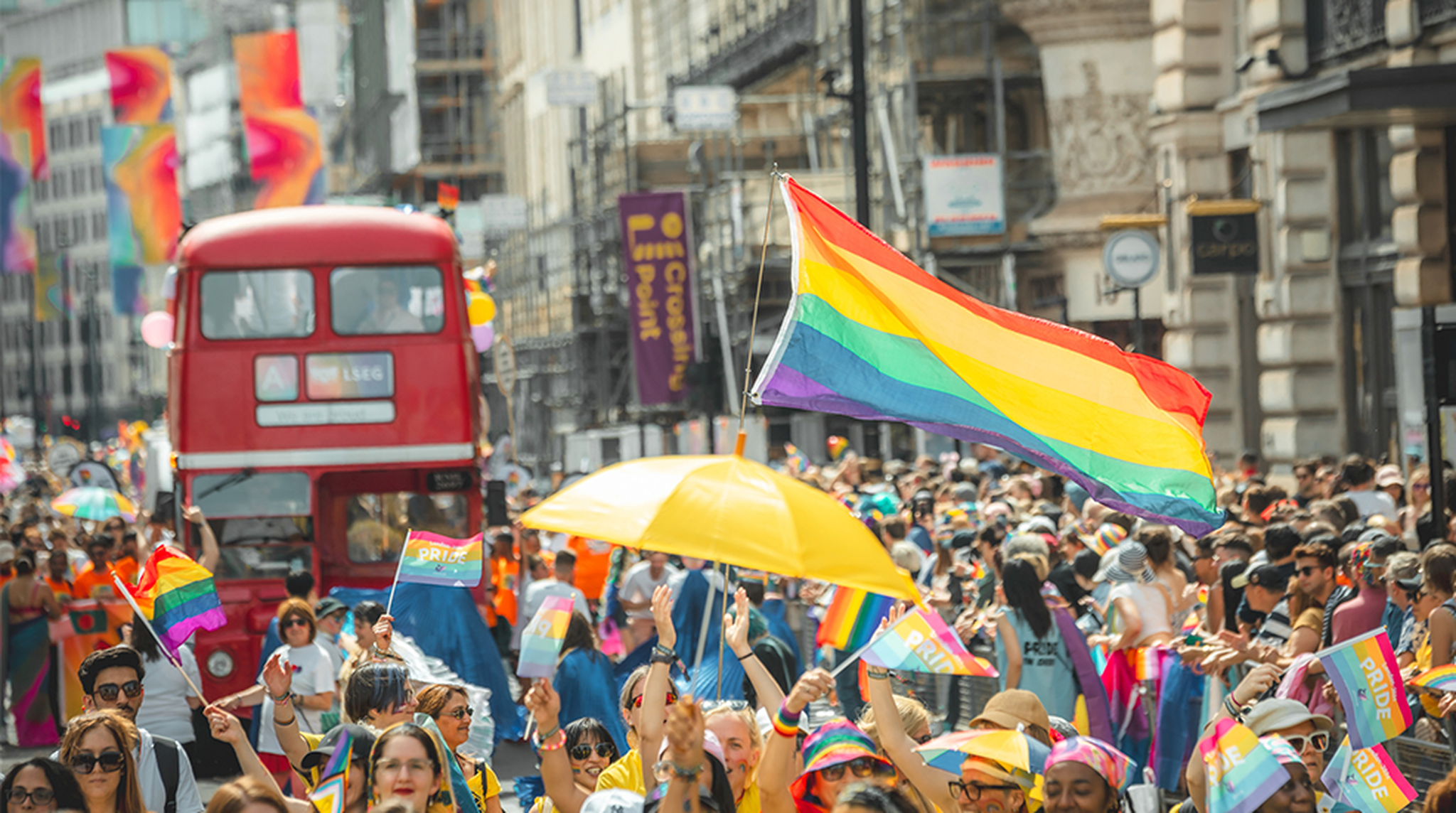 London Pride parade featuring iconic red bus and Pride flags