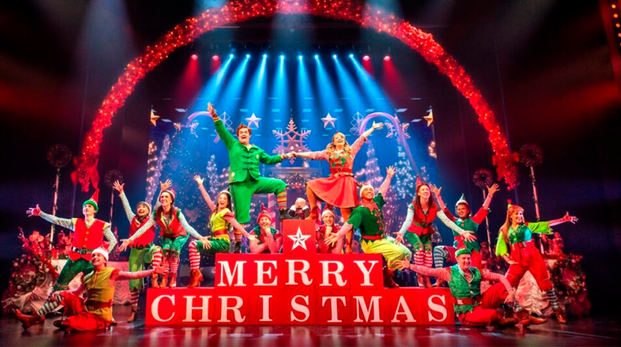 Performers in festive costumes dance on stage