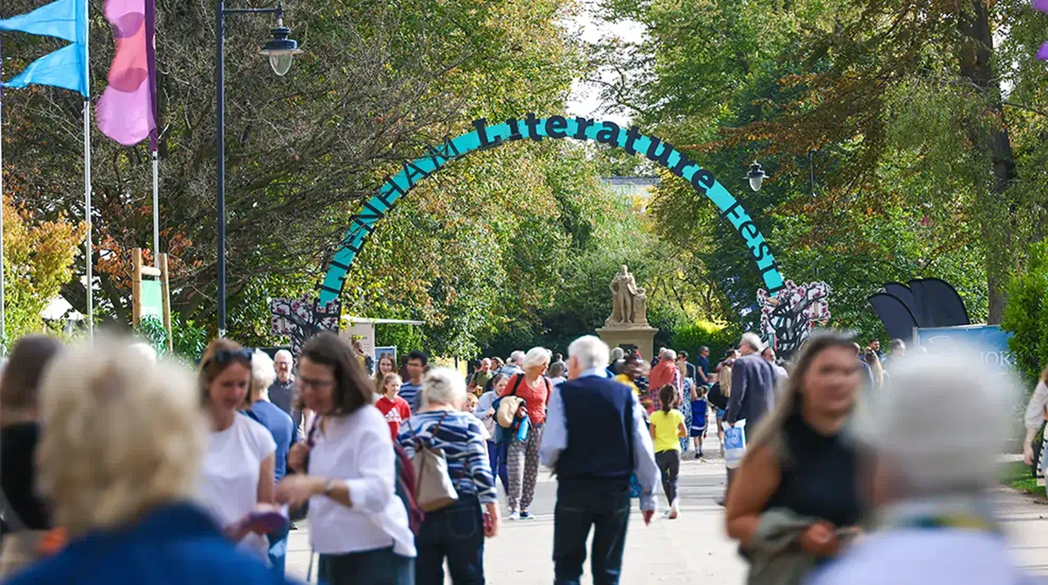 People walking through an outdoor literature festival, with a decorative archway