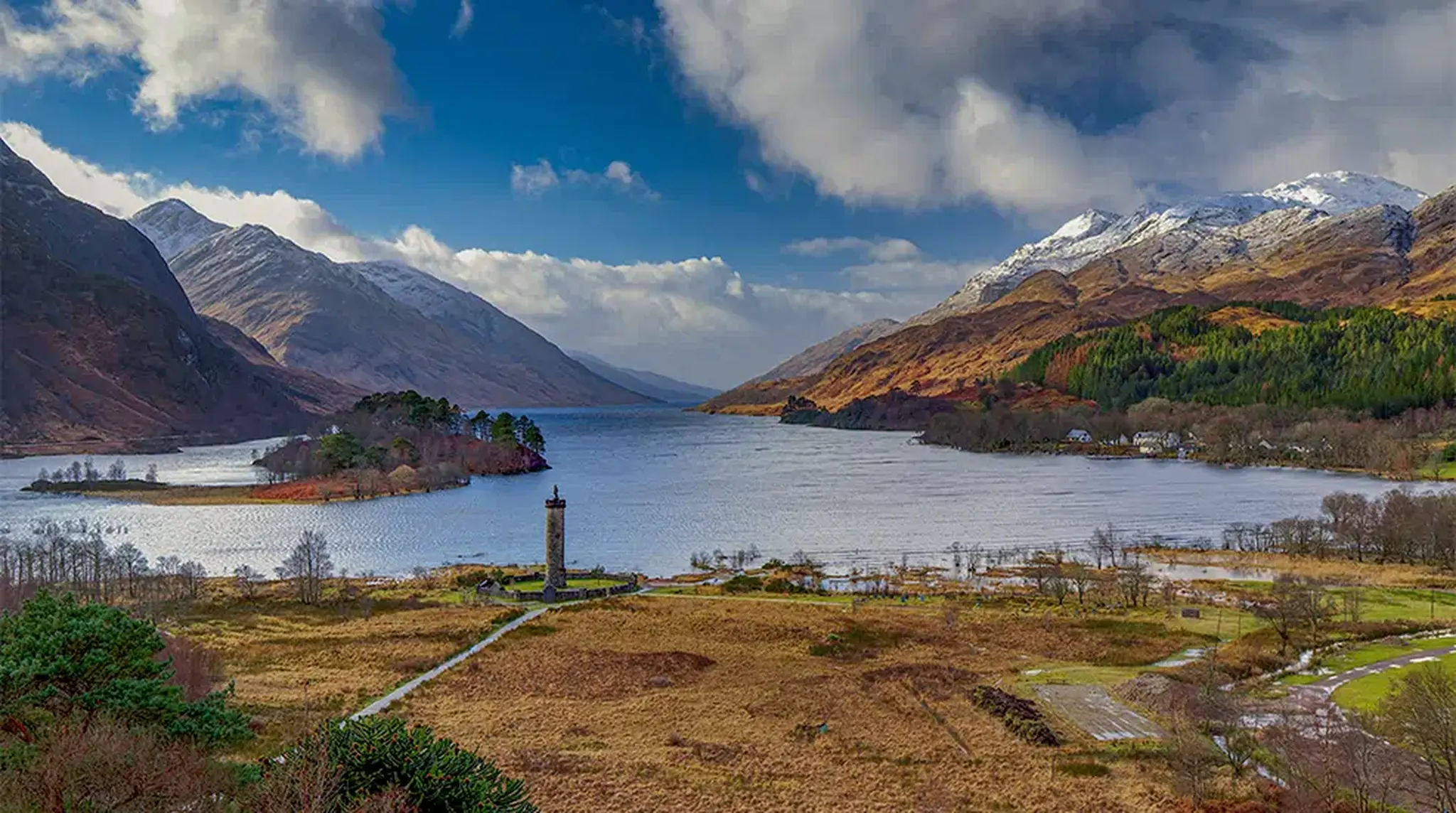 Scenic view of Loch Shiel with a monument in the foreground, surrounded by mountains