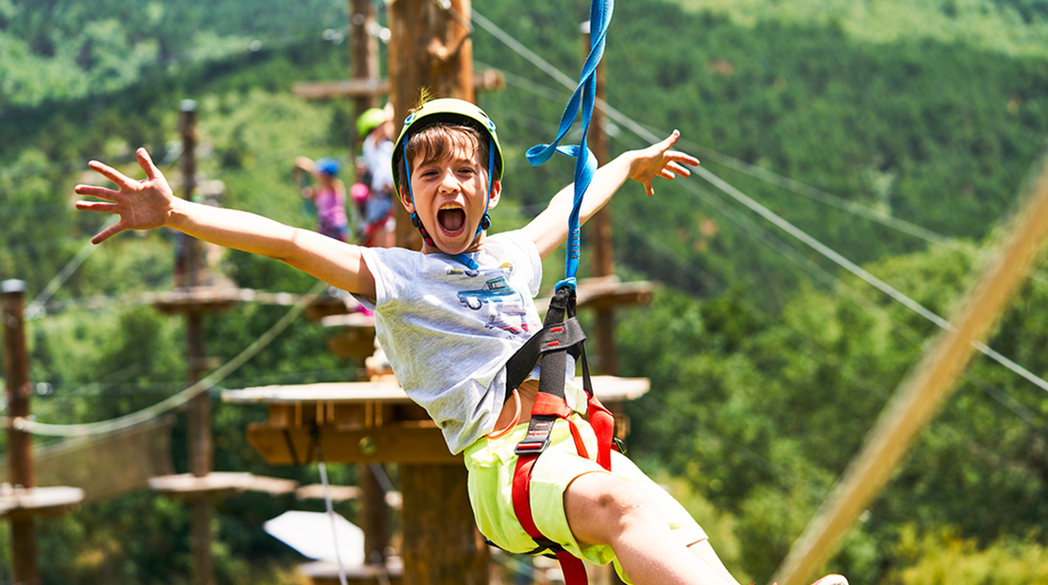 Young boy screaming with joy while ziplining through an adventure park
