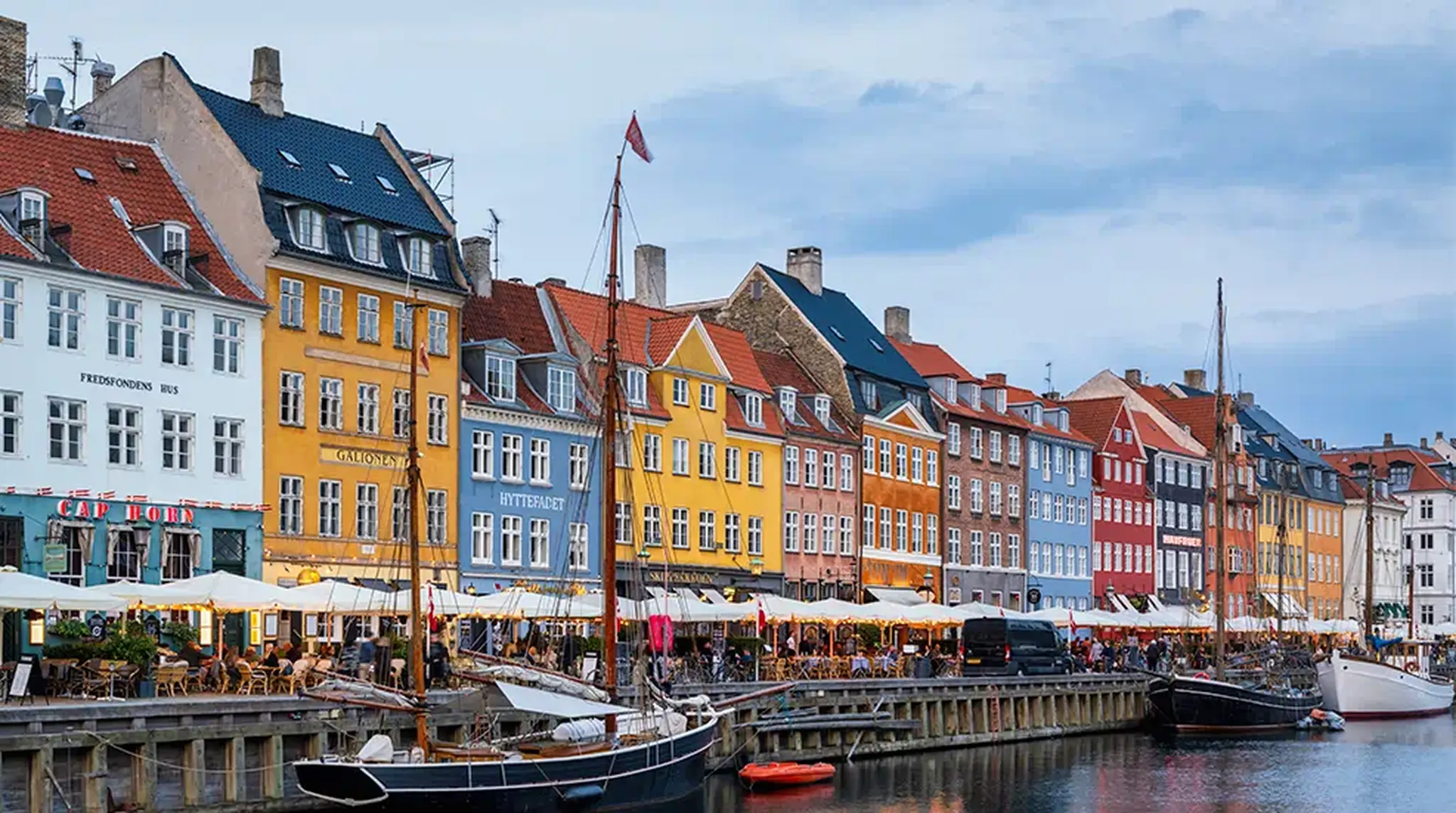 Colourful historic buildings line the waterfront in Nyhavn, Copenhagen, with boats docked along the canal