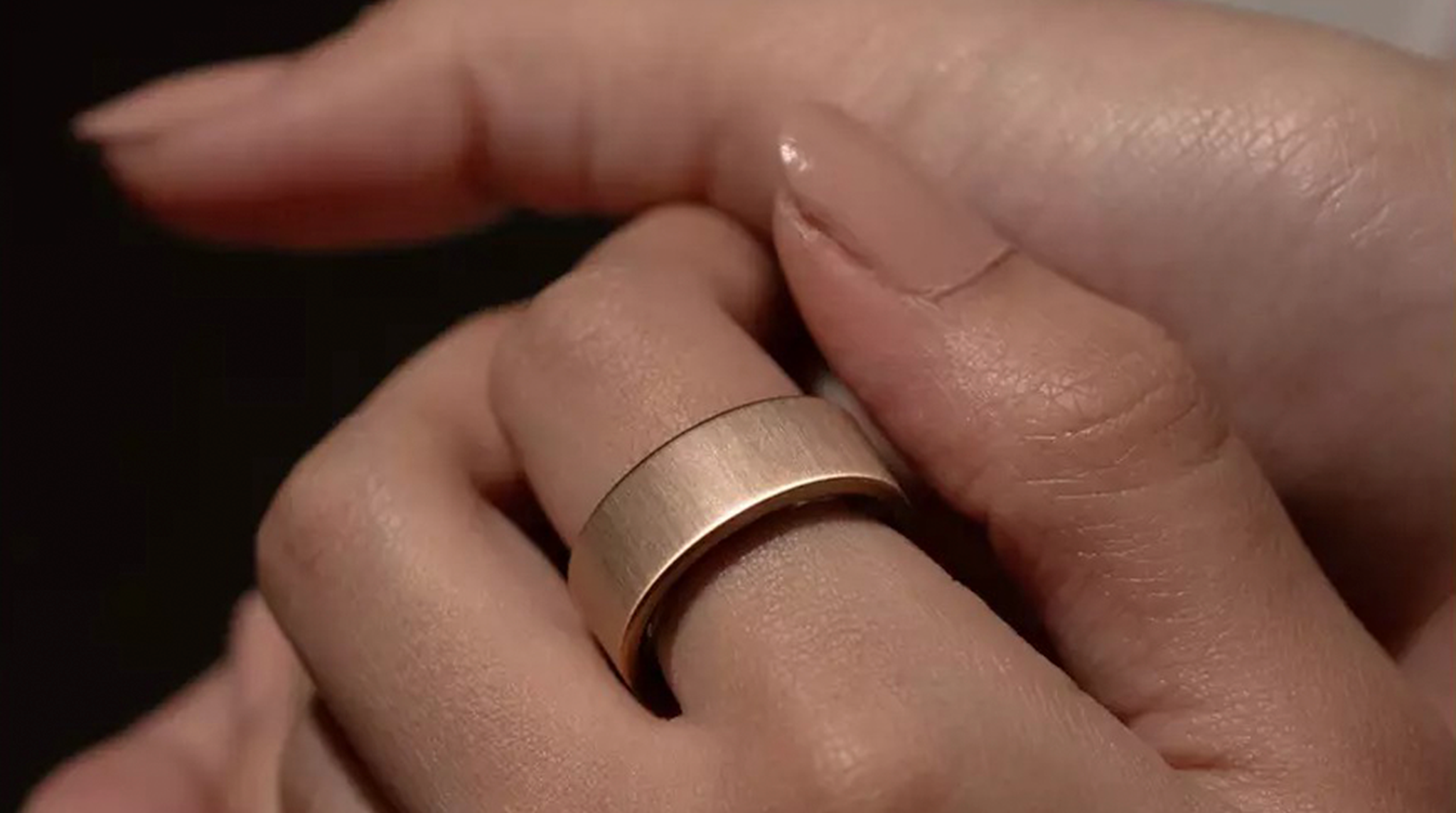 Close-up of a hand wearing a matte gold Ultrahuman Ring AIR smart ring