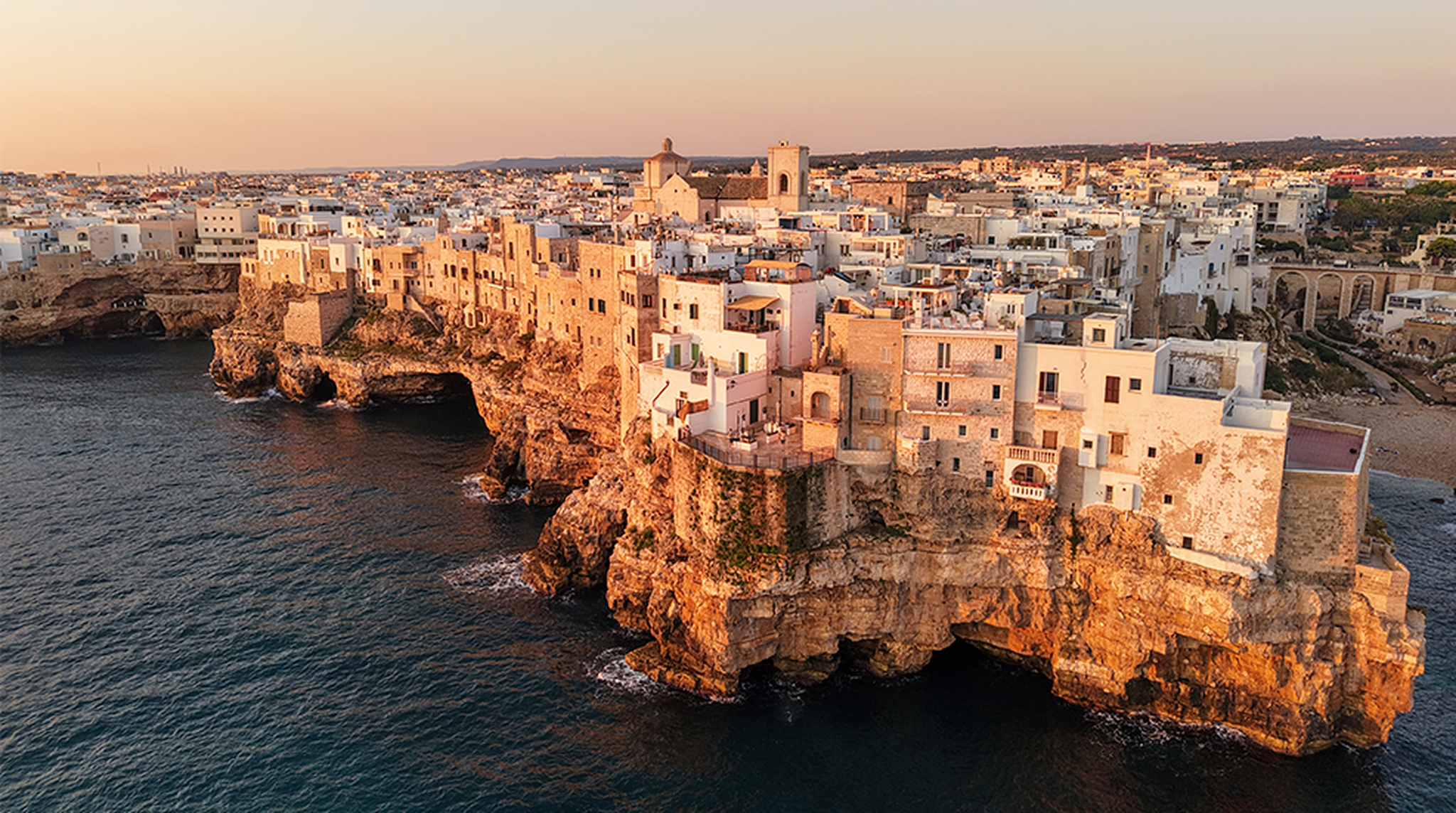 Aerial view of Polignano a Mare with white buildings, cliffside layout, and coastal scenery, Puglia, Italy