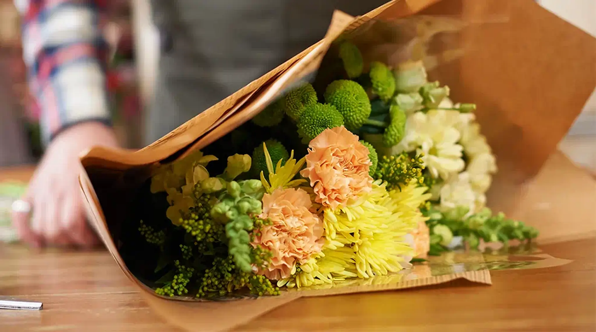 Bouquet of yellow, peach, and green flowers wrapped