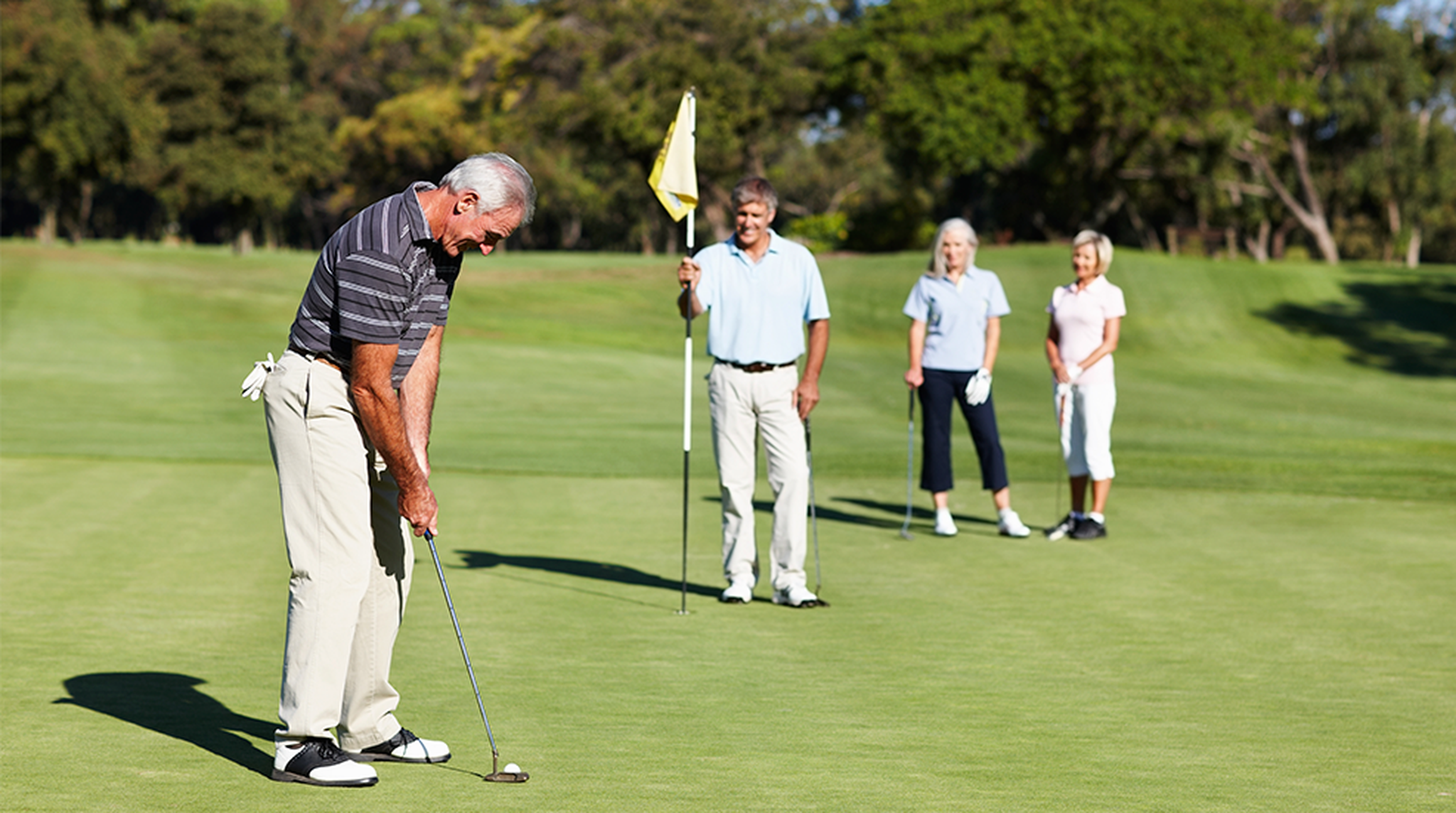 Male golfer on putting green about to put the ball in the hole