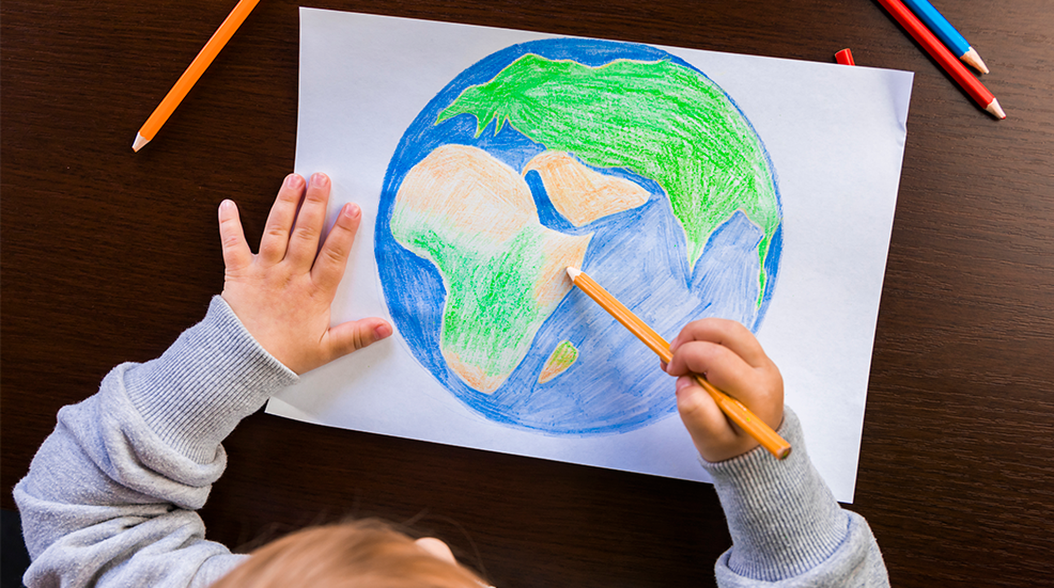 Girl draws earth with pencils