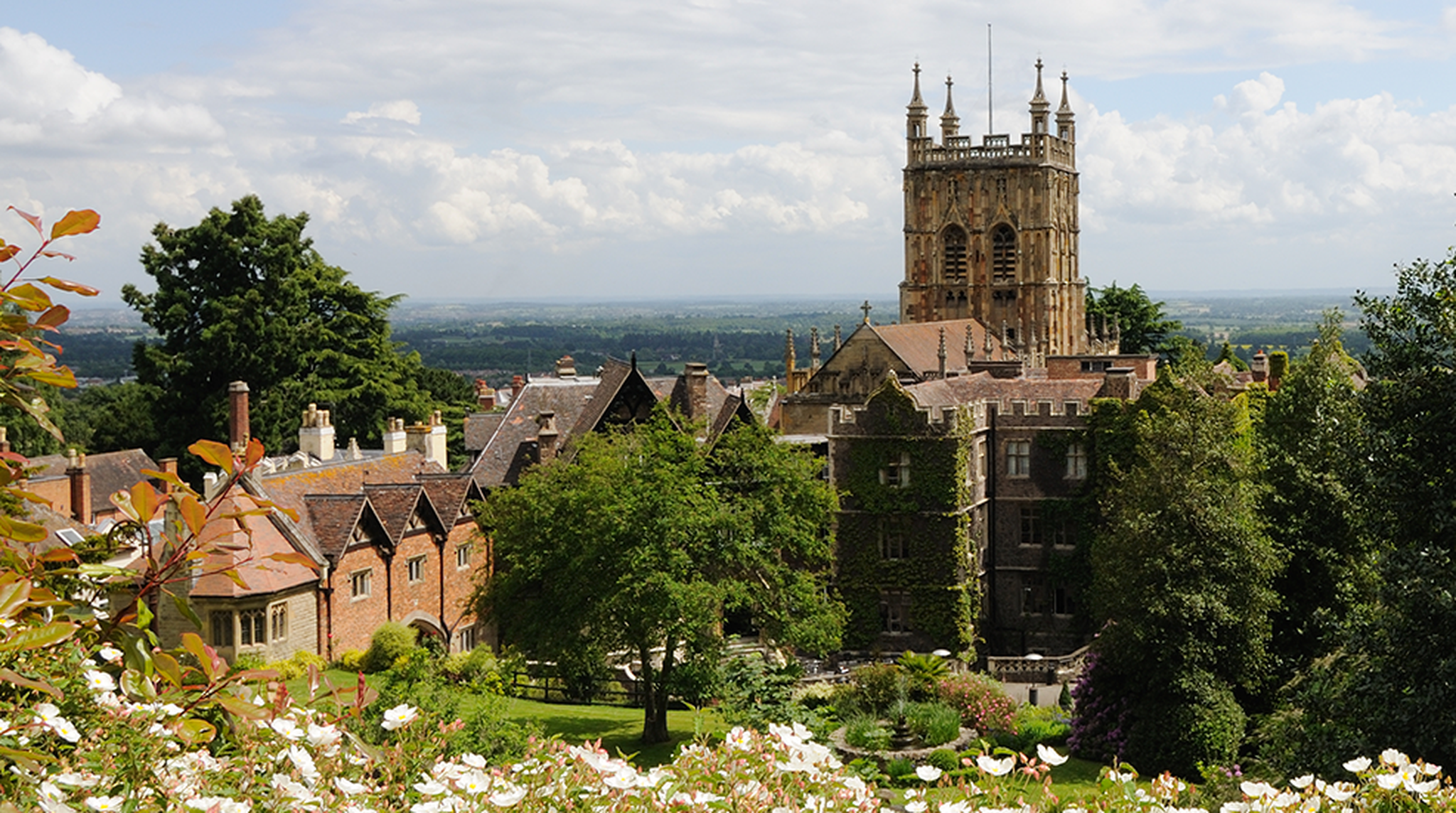 Malvern Priory and Hotel - stock photo Looking west over Malvern Priory and the Abbey Hotel towards the Vale of Evesham and the River Severn. Cistus (Rock Rose) in flower in foreground.