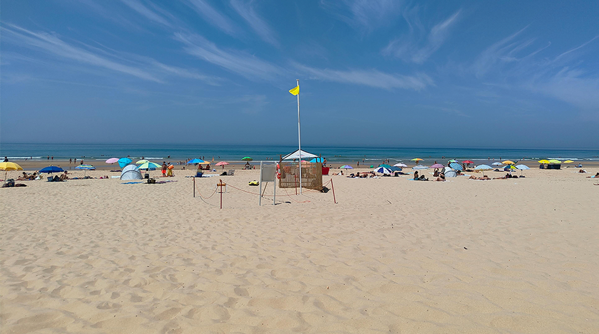 Beautiful sunny day at Costa da Caparica, Portugal, with vibrant beach umbrellas and a clear blue sky.