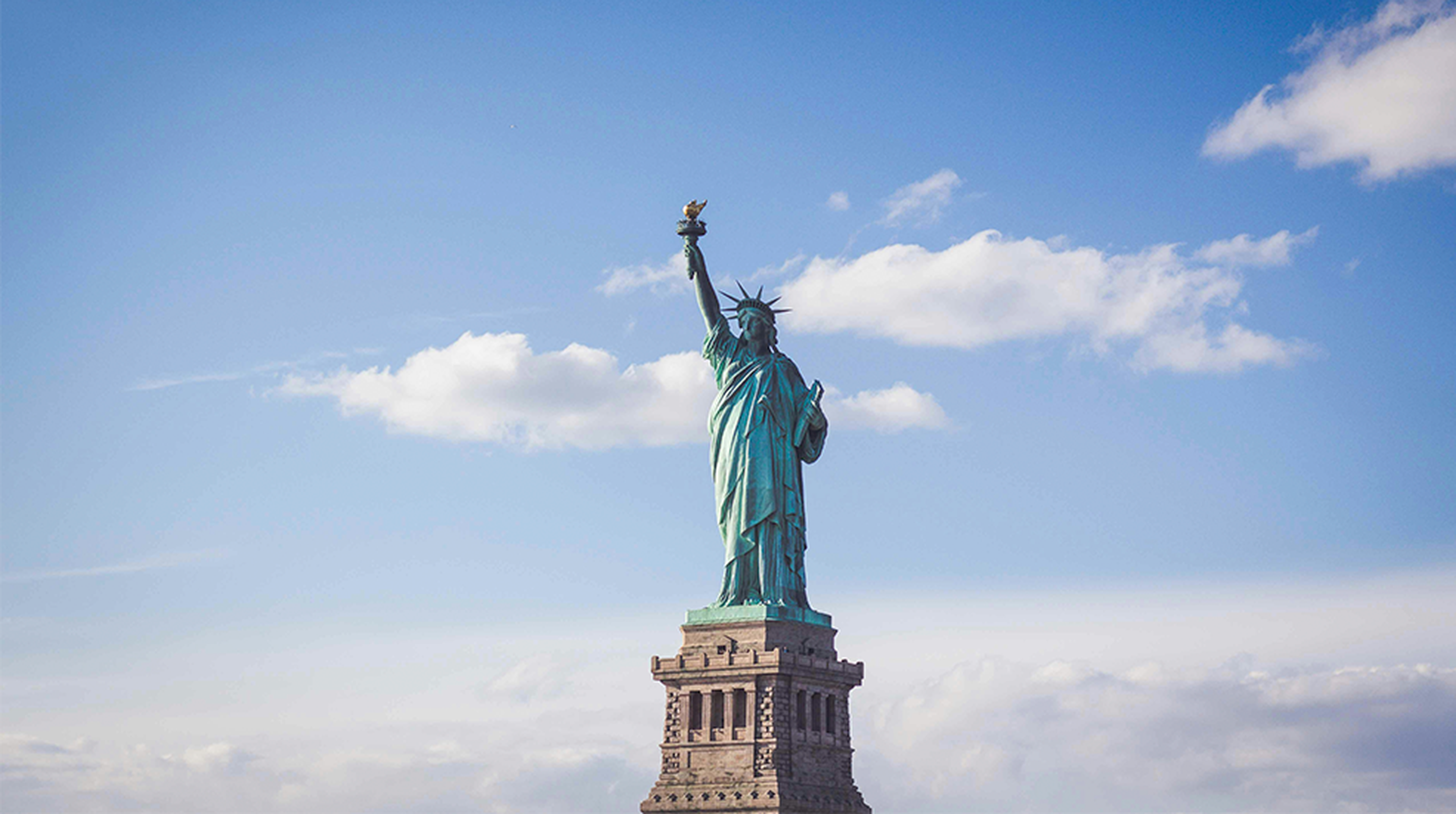 Statue of Liberty, New York under white and blue cloudy skies