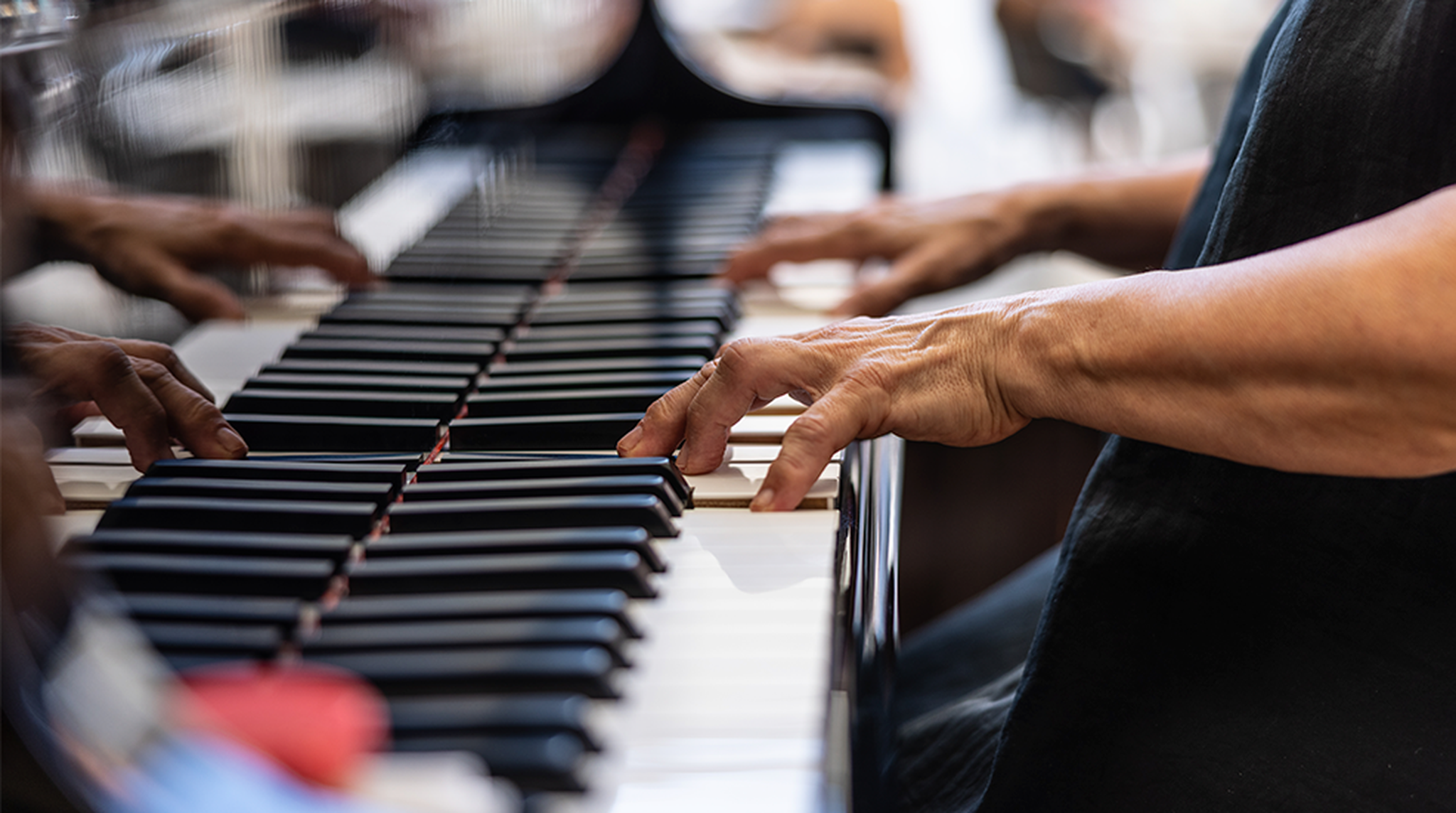 Close-up view of elderly woman's hands playing a melody on the piano during piano lessons
