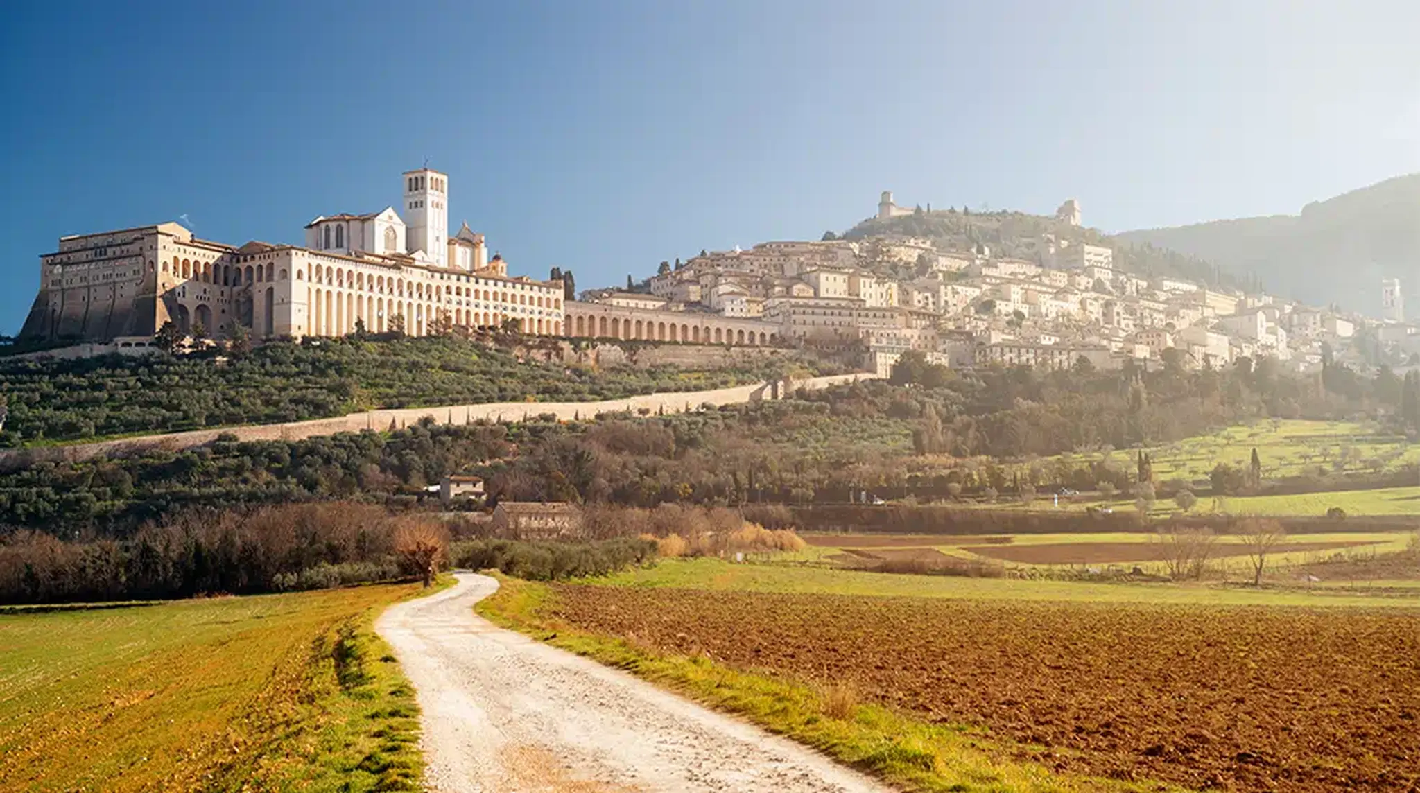 A scenic view of Assisi, Italy, featuring historic buildings with a winding path