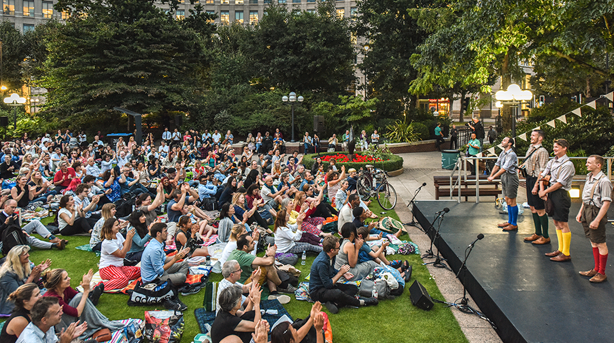 Audience sat on grass for Alfresco Arts in Canary Wharf