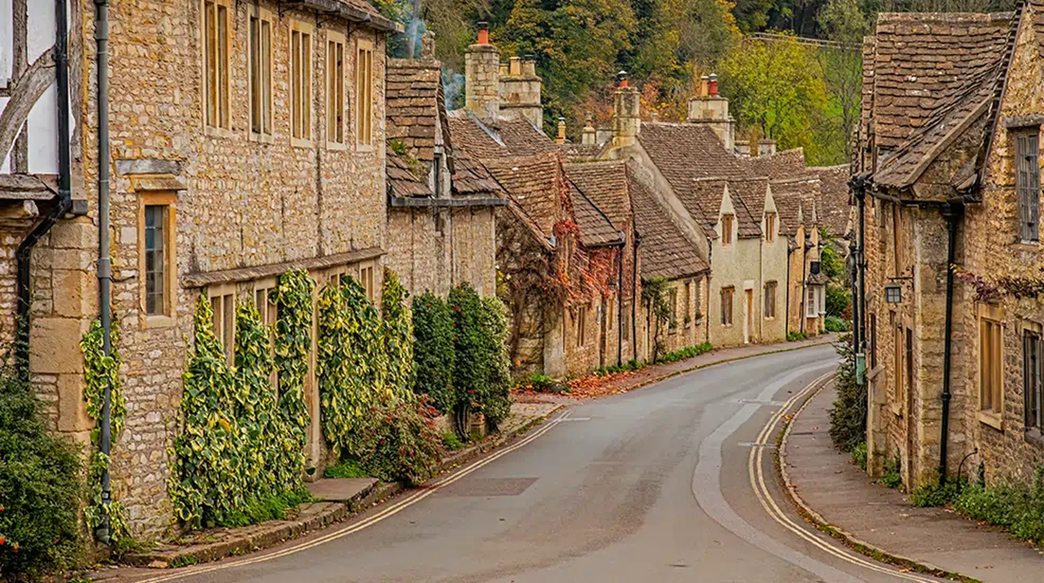 Quaint stone Cotswolds cottages lining a narrow, winding road