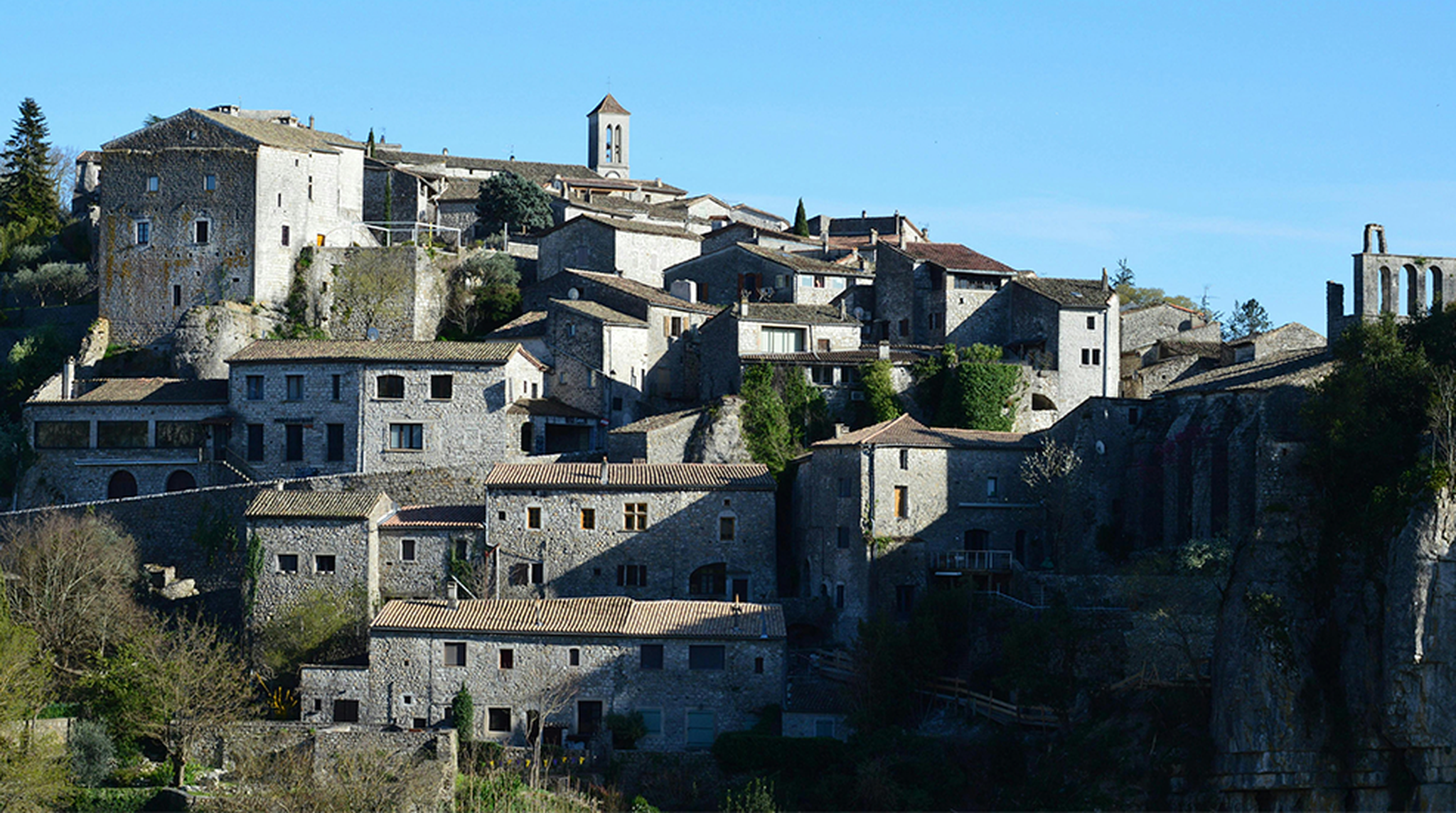 A scenic view of Balazuc village in France with stone buildings under a clear sky.
