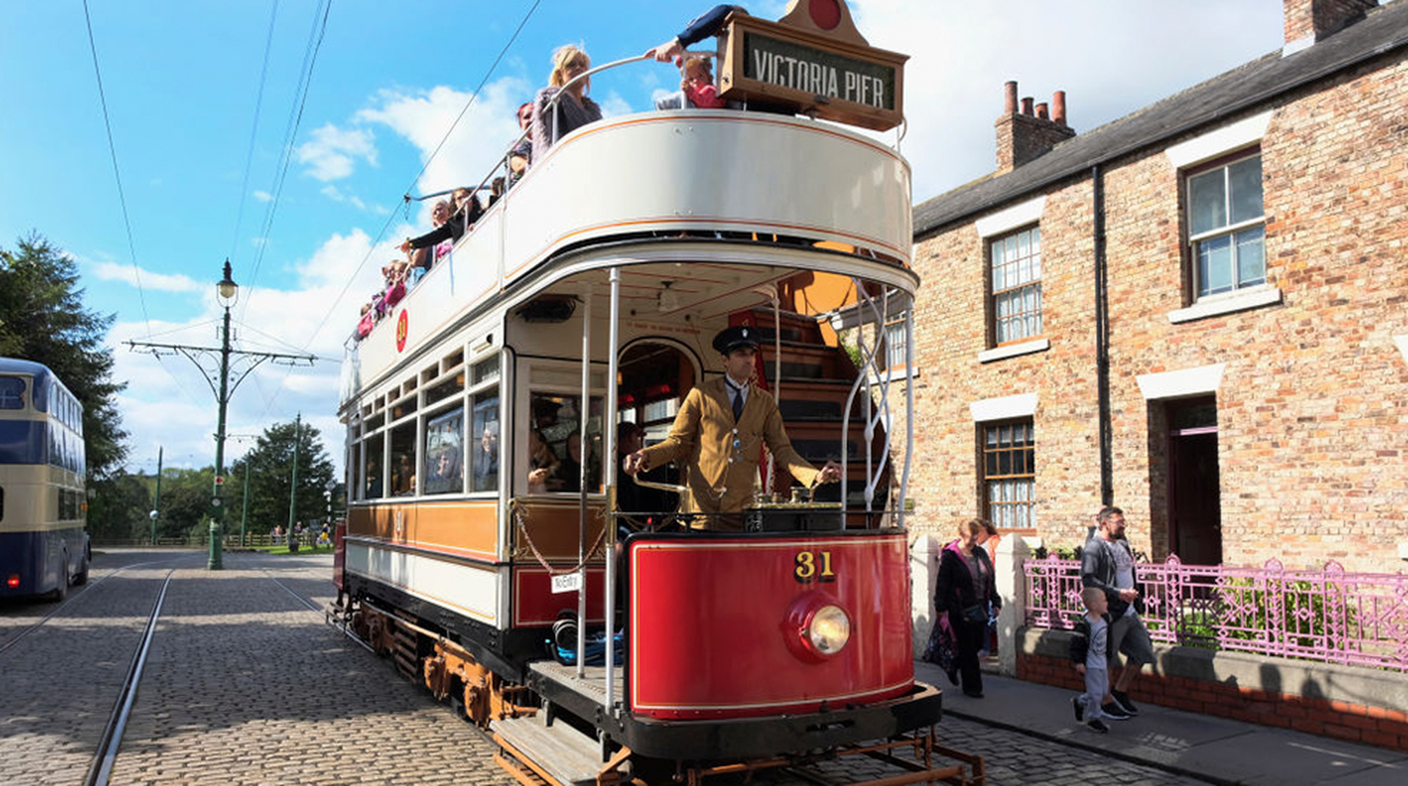 England, County Durham, Beamish, Street with electric tram full of tourists