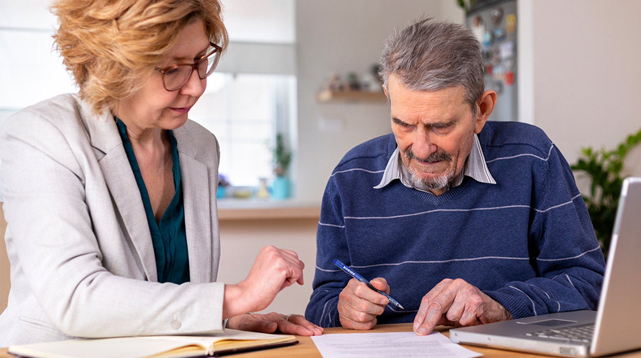 Mature woman helping senior man, 91 years old, with paperwork