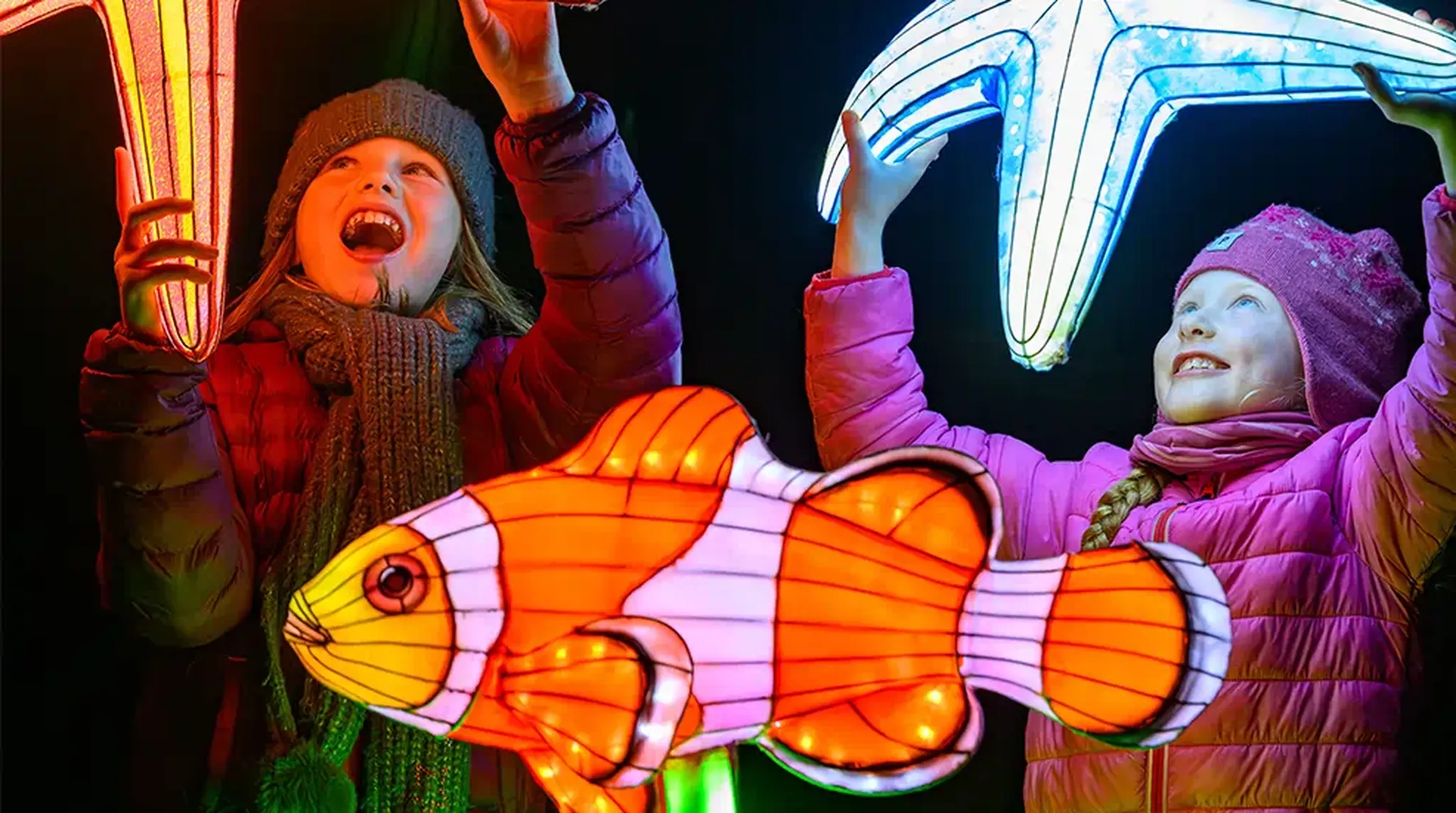 Two children joyfully hold glowing starfish lanterns