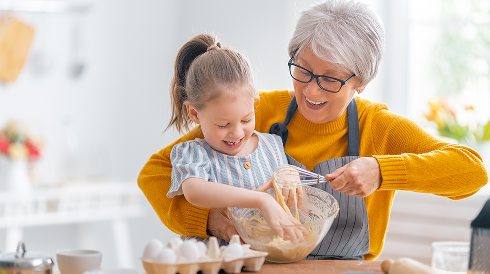 Granny and child are cooking cookies and having fun in the kitchen