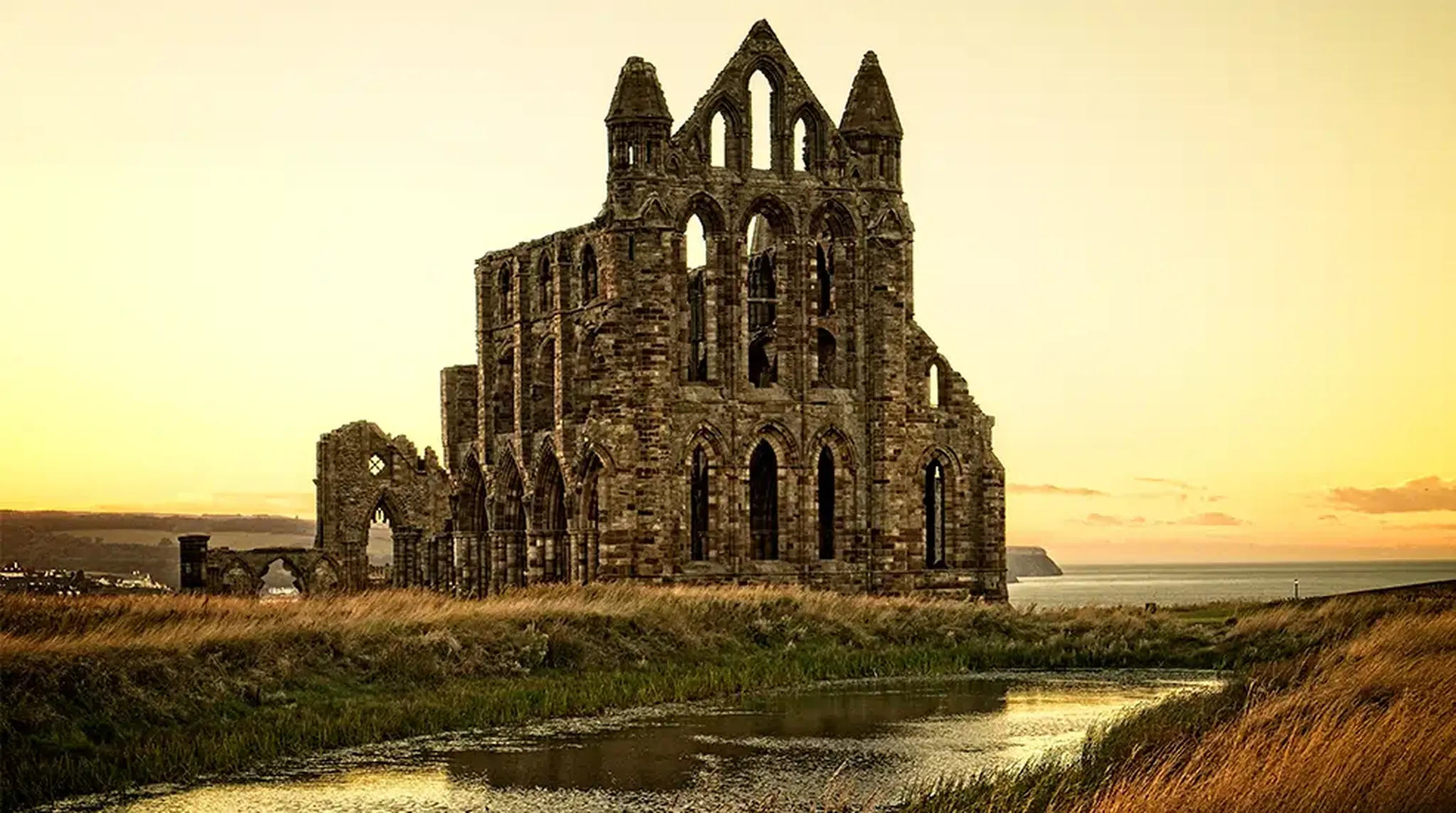 Ruins of a Gothic abbey silhouetted against a sunset sky